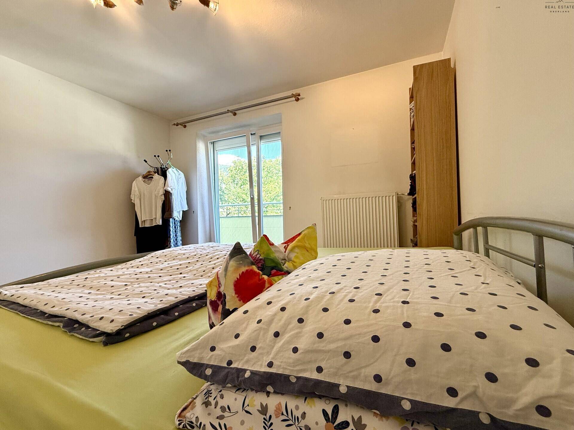 Gemütliches Schlafzimmer mit farbenfrohen Kissen und Blick auf den Außenbereich.