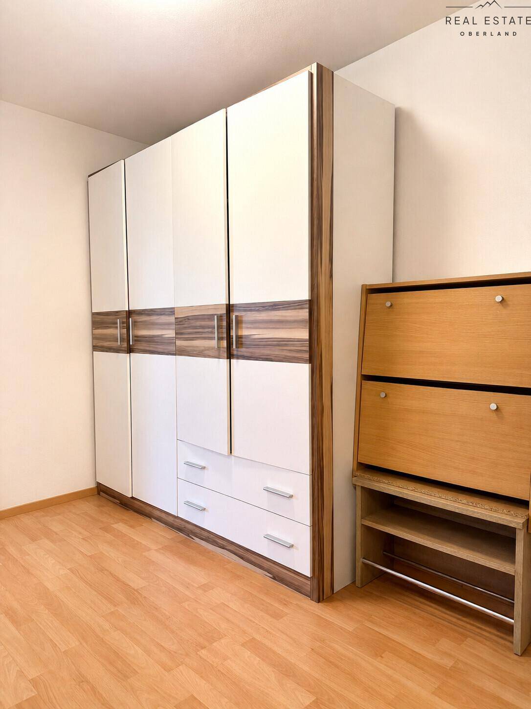 Geräumiger Kleiderschrank mit Holz- und Weißfronten, bietet viel Stauraum.