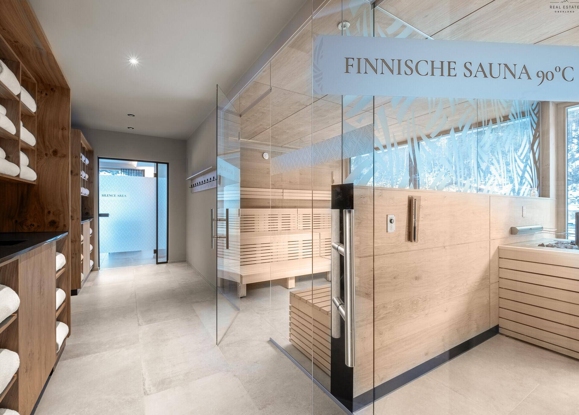 Eingang zur finnischen Sauna mit Holzvertäfelung und praktischen Handtuchregalen.