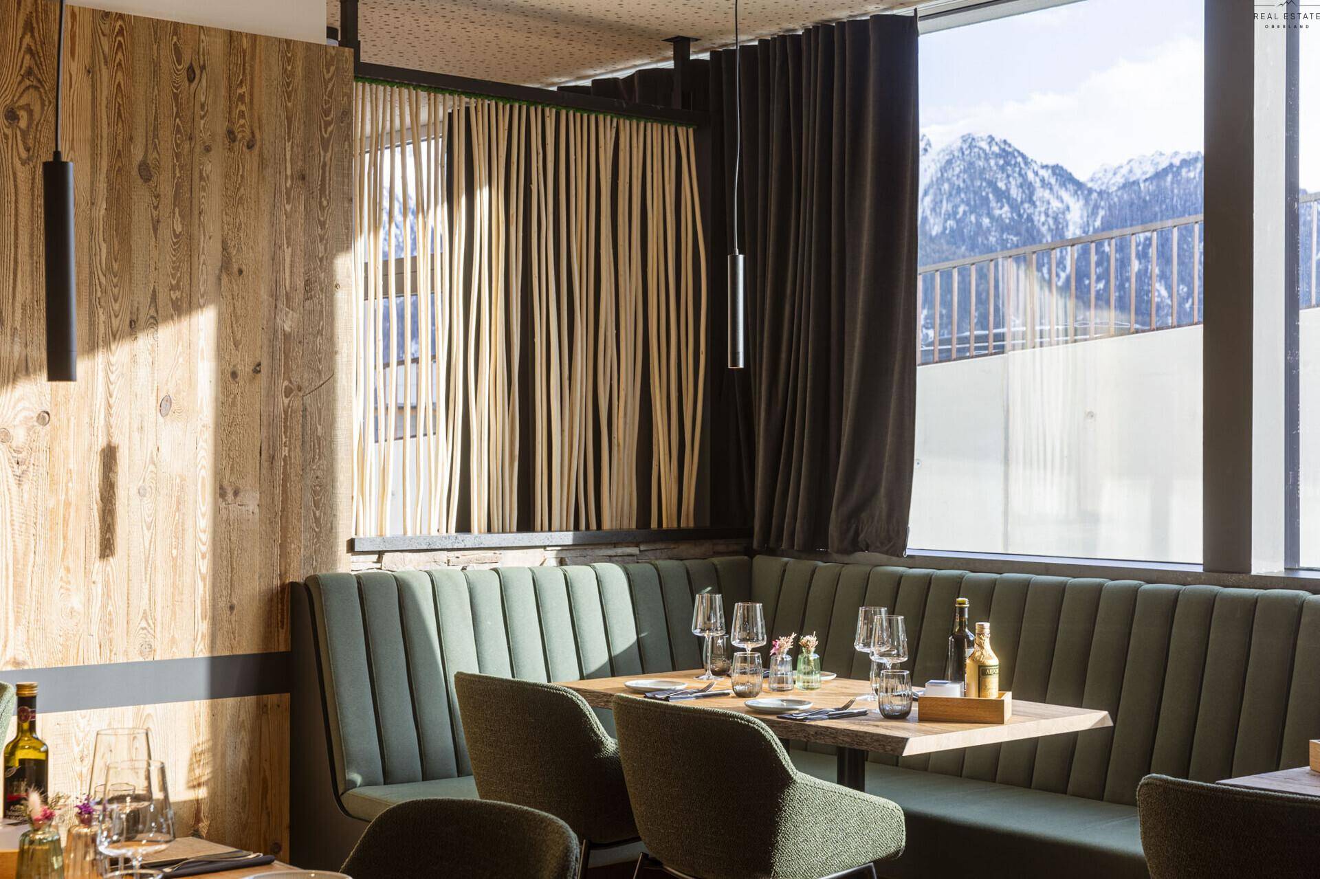 Gemütlicher Essbereich mit Sitzbänken, Holzwand und einem Fenster, das einen Blick auf die Berge bietet.
