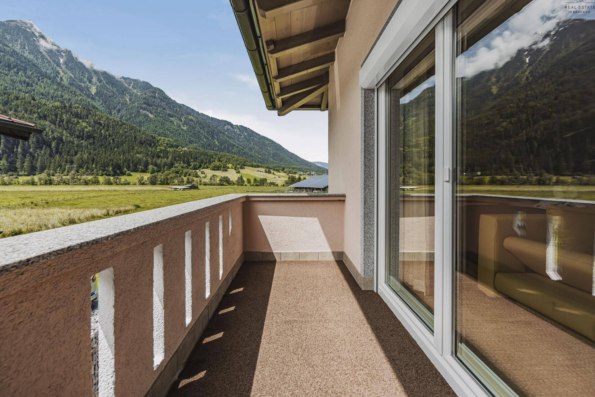Sonniger Balkon mit weitem Blick auf die grüne Berglandschaft und das Tal.