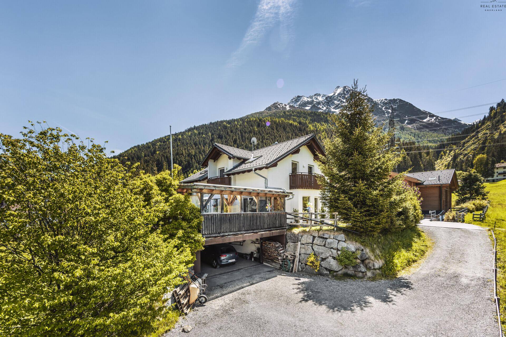 Charmantes Haus in den Bergen mit Balkonen, Carport und umgebender Natur.