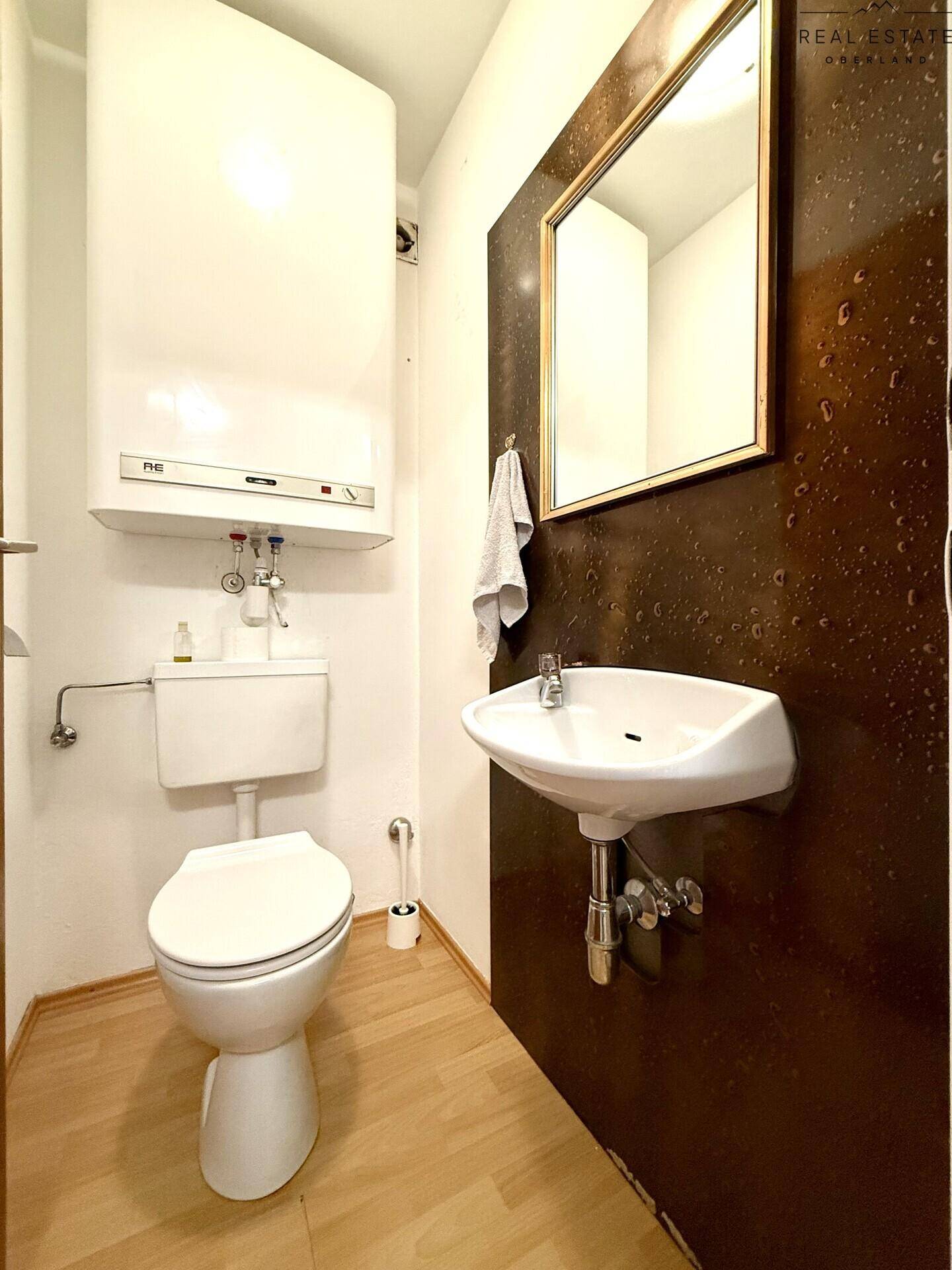 Kleines Gäste-WC mit Toilette, Waschbecken und Boiler.