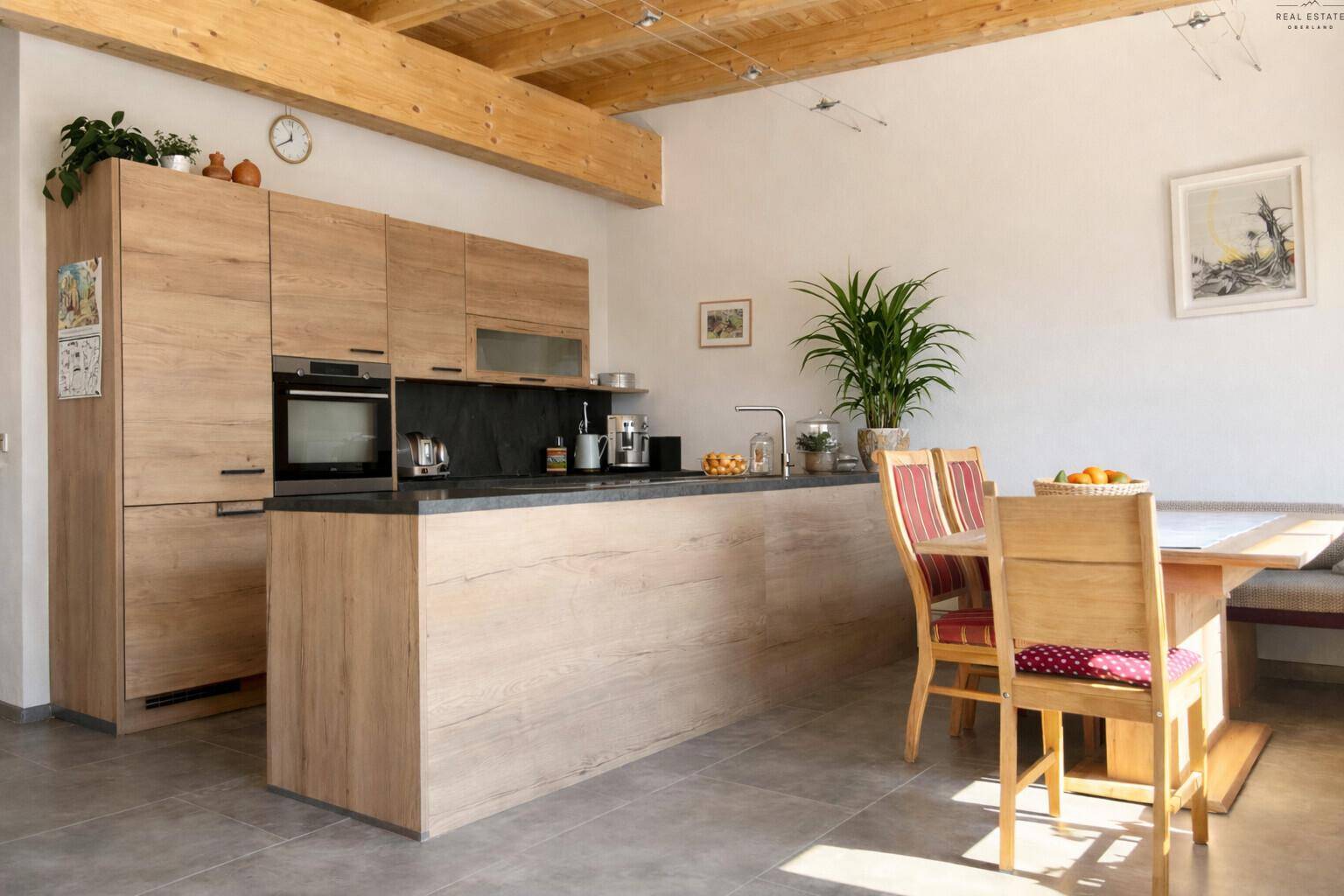 Geräumige Wohnküche mit Holzelementen, Essbereich und sichtbaren Deckenbalken, hell und einladend.