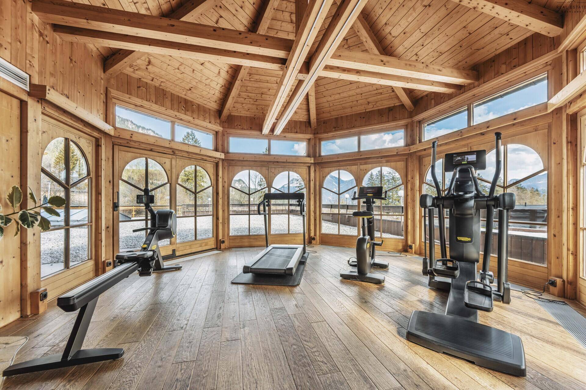 Heller Fitnessraum mit modernen Geräten und Panoramablick auf die Berge.