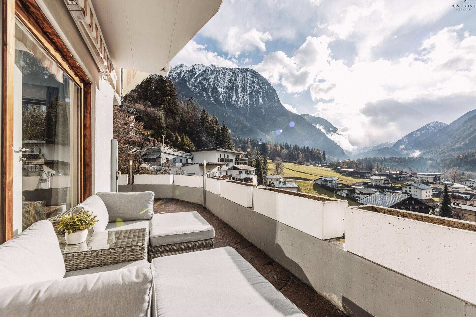 Geräumiger Balkon mit bequemen Loungemöbeln und atemberaubendem Panoramablick auf die Berge.