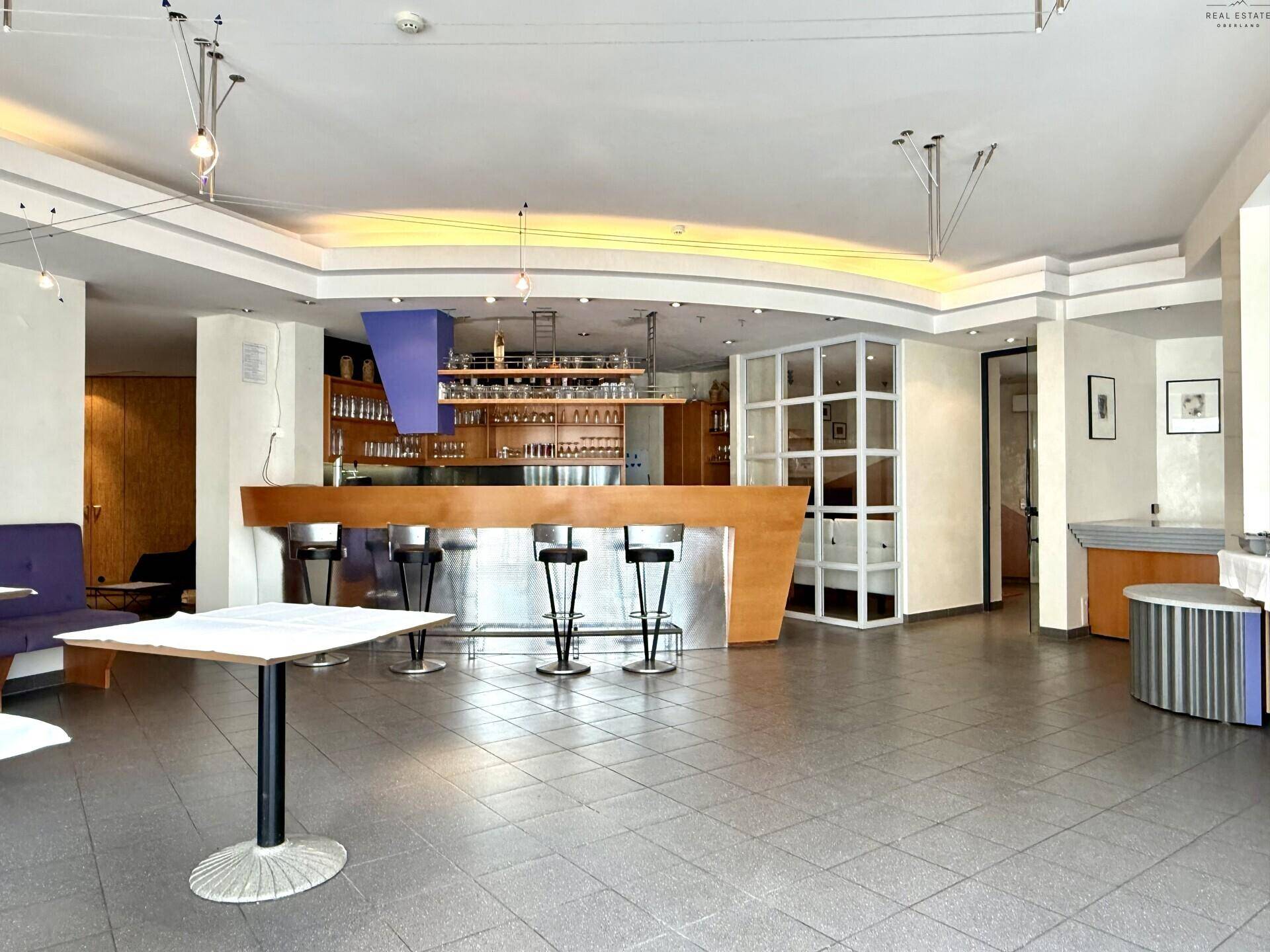 Bar- und Loungebereich mit moderner Theke, Hockern und indirekter Beleuchtung.