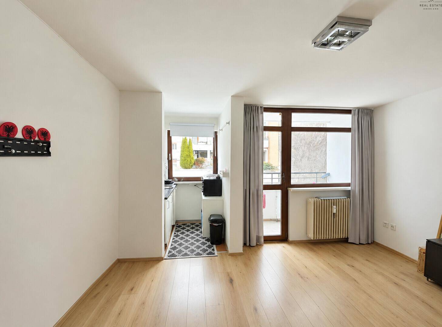 Helles Wohnzimmer mit Laminatboden, großem Fenster und Zugang zu einem kleinen Balkon.