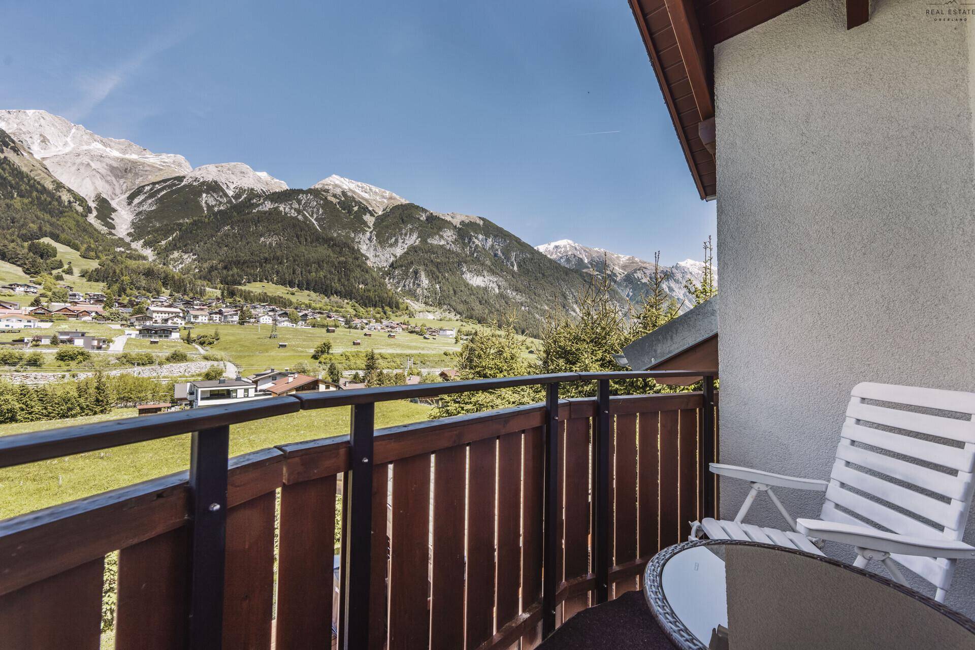 Gemütlicher Balkon mit Sitzgelegenheit und spektakulärem Blick auf die Alpen.