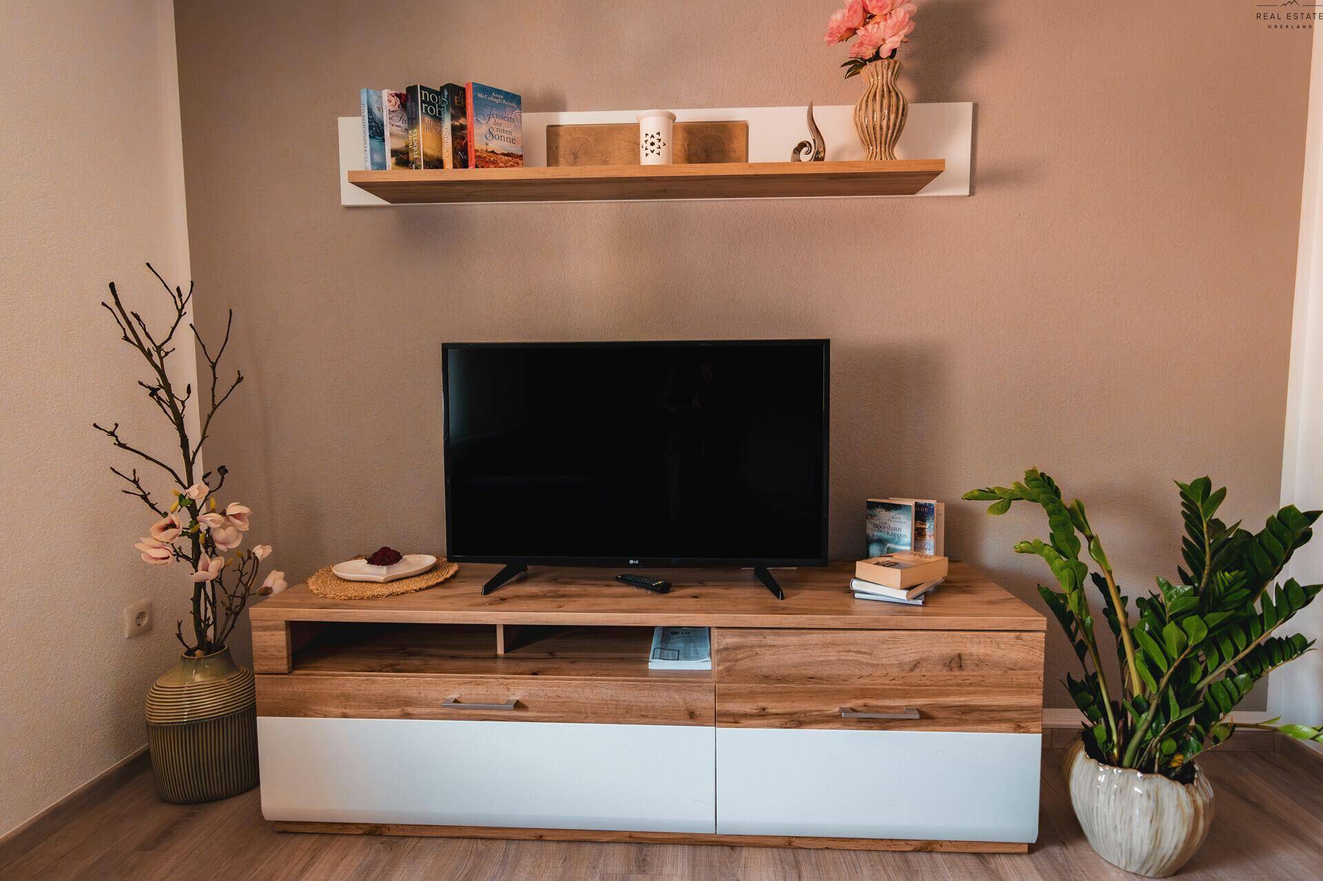 Wohnzimmerbereich mit Fernseher auf einem modernen Holzschrank und stilvoller Dekoration.