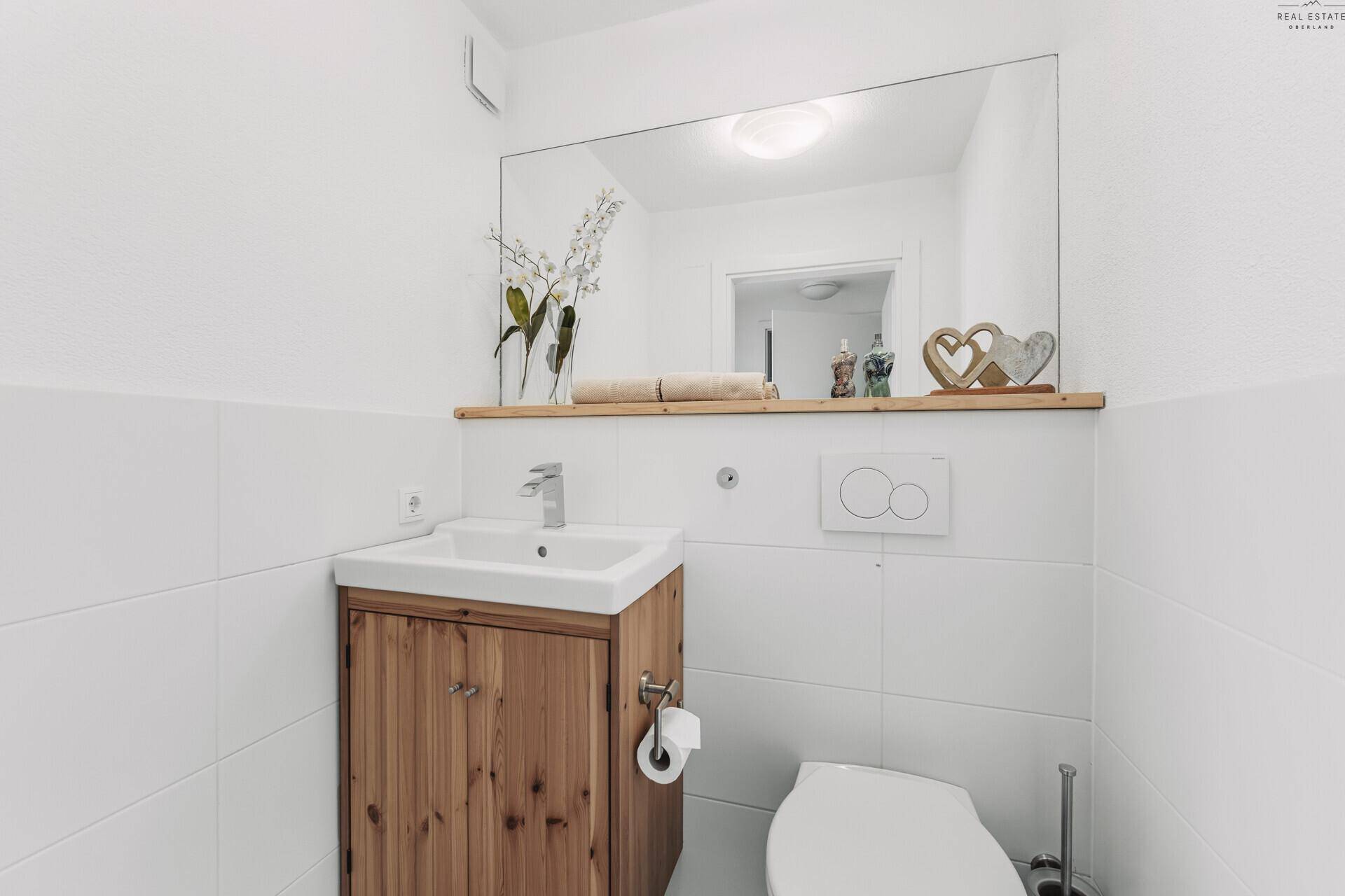 Kleines Gäste-WC mit Holzwaschtisch, Spiegel und Wand-WC.