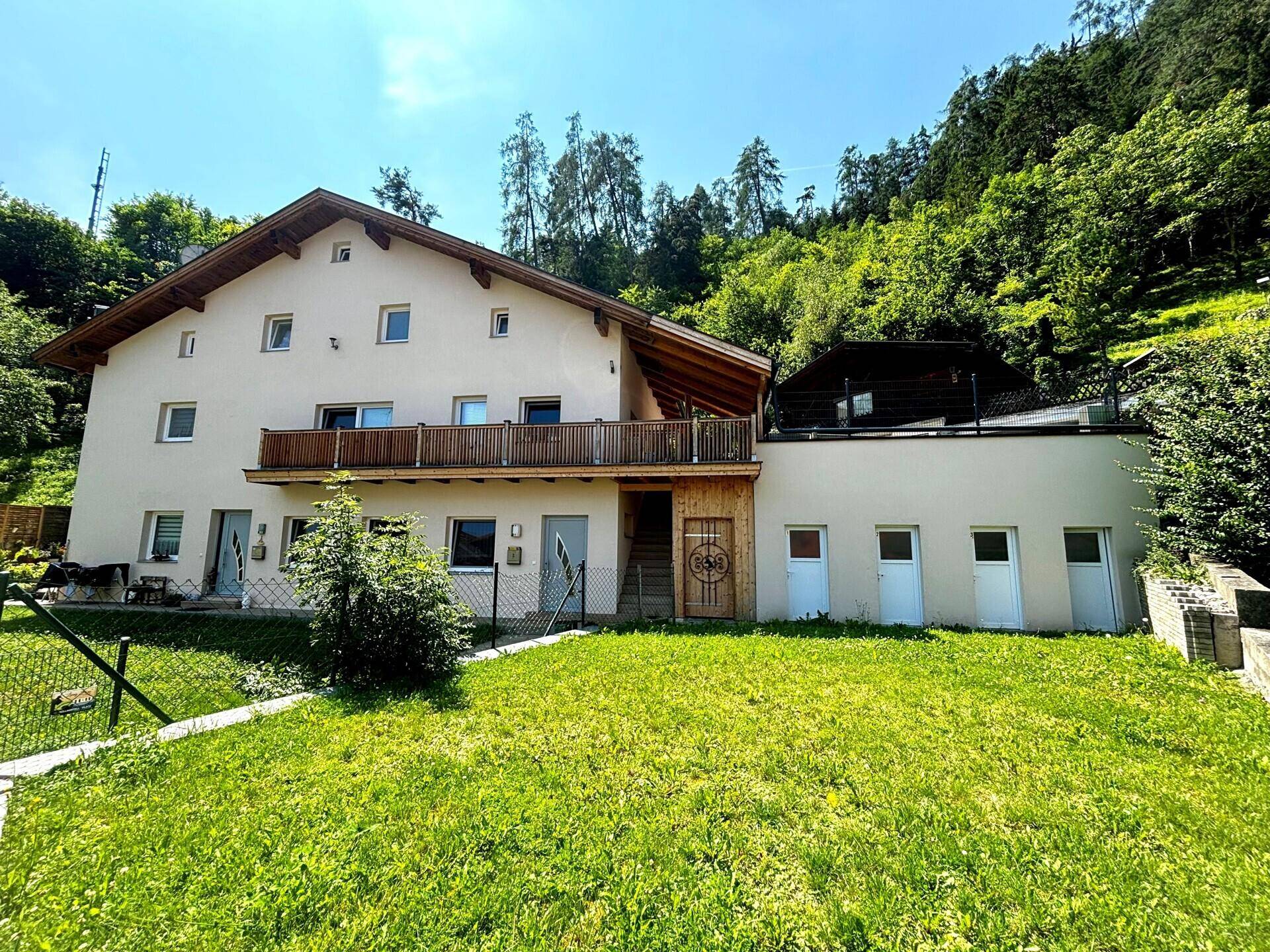 Mehrfamilienhaus mit Balkonen und gepflegtem Rasen in grüner Umgebung.
