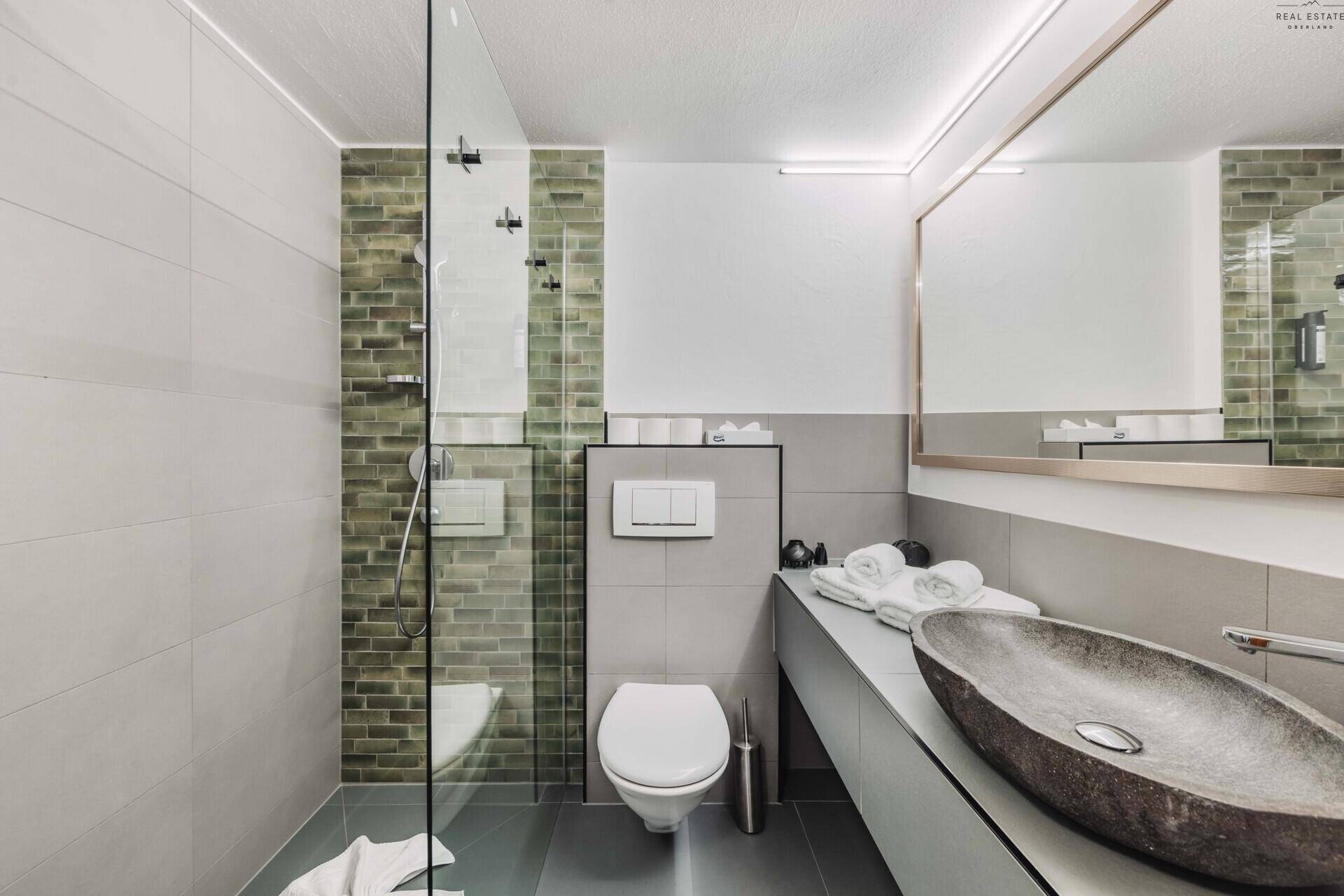 Modernes Badezimmer mit begehbarer Dusche, Wand-WC und stilvollem Steinwaschbecken.