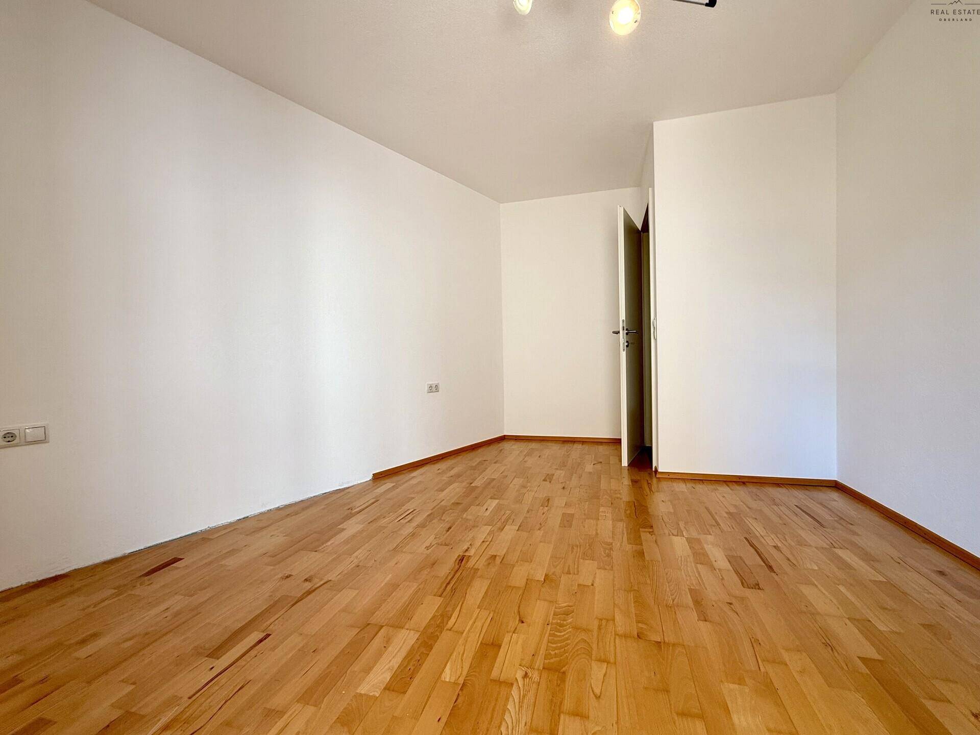 Schlafzimmer mit Holzboden, weißen Wänden und ausreichend Platz für Möbel.