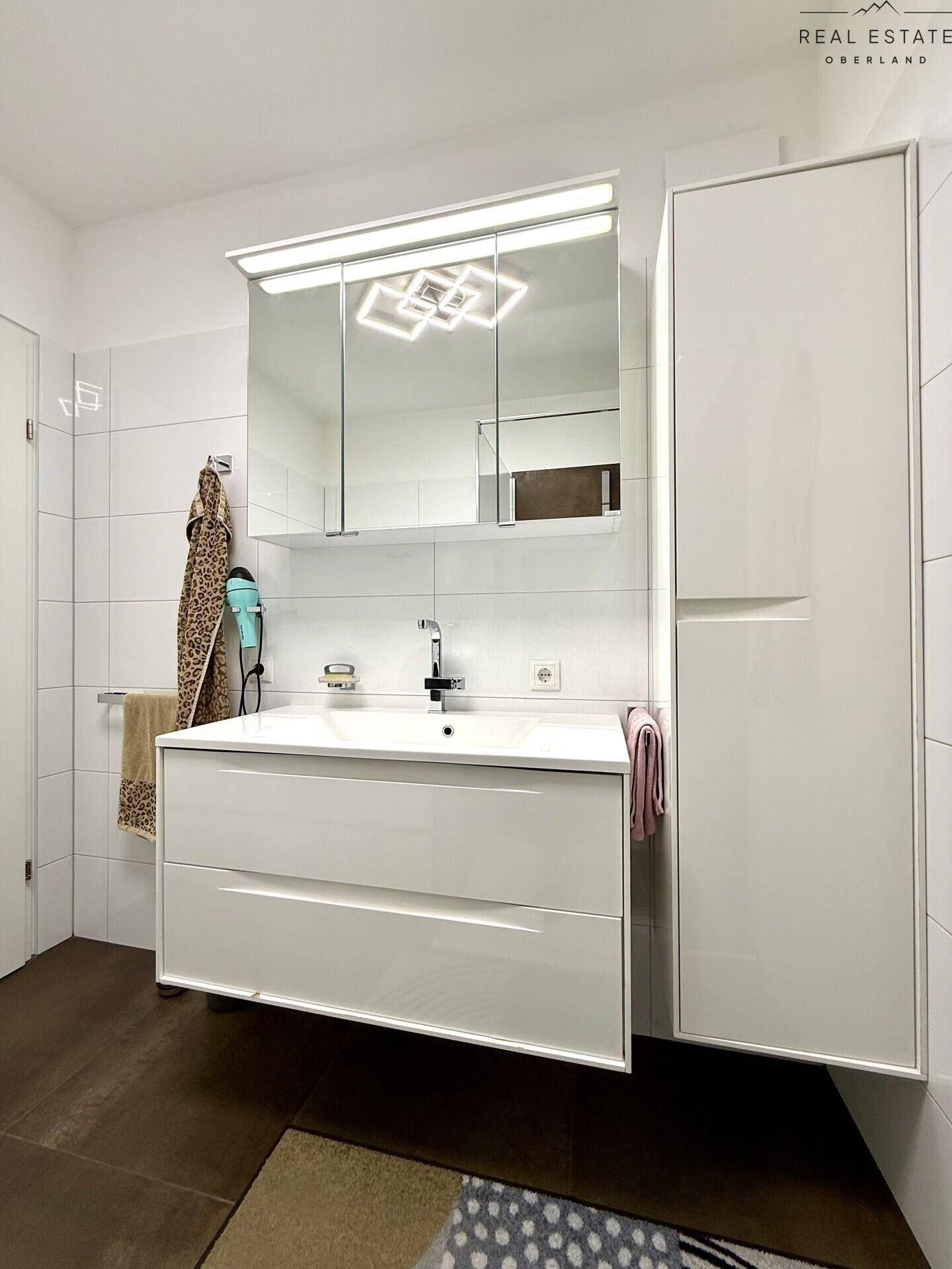 Badezimmer mit modernem Waschtisch, Spiegelschrank und viel Stauraum.
