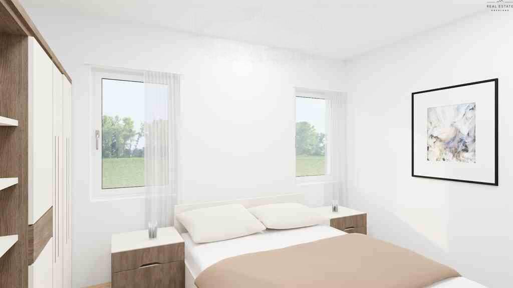 Schlafzimmer mit Doppelbett, Nachttischen und Blick ins Grüne durch große Fenster.