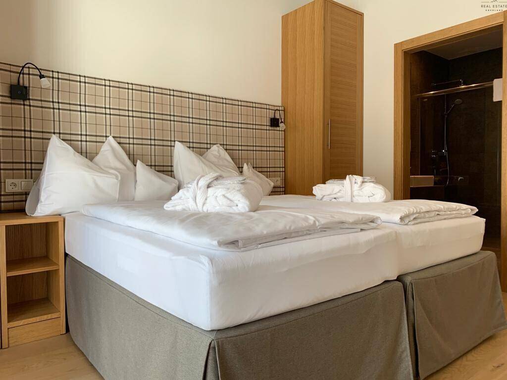 Komfortables Schlafzimmer mit Doppelbett, Holzschrank und Zugang zu einem angrenzenden Bad.