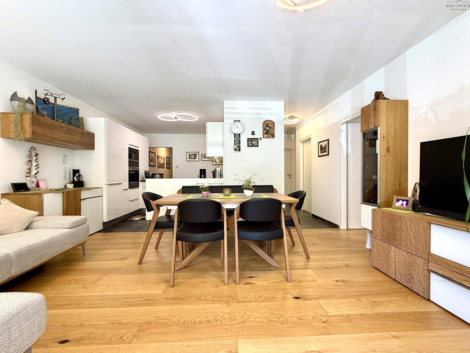 Geräumiger Wohn-Essbereich mit Holzboden, großem Esstisch und gemütlichem Sofa.