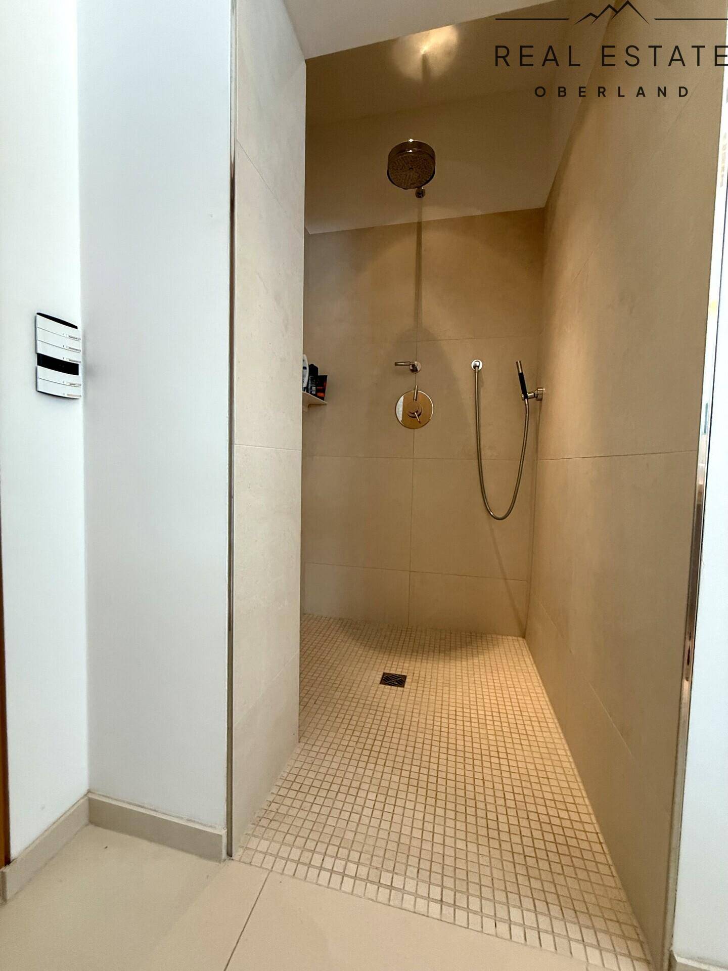 Moderne begehbare Dusche mit hellen Fliesen und Mosaikboden, bietet Komfort und Stil.