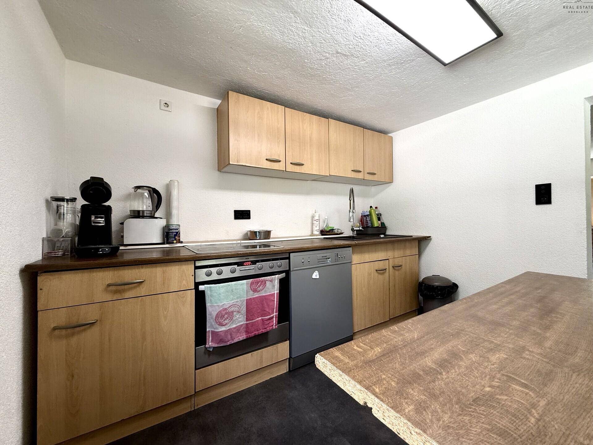 Funktionale Küche mit Holzfronten, Spülmaschine und Backofen, ideal für den täglichen Gebrauch.