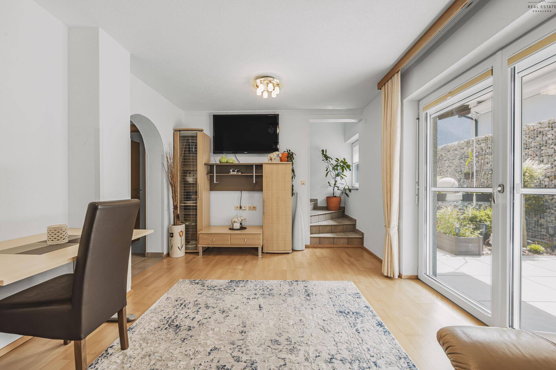 Geräumiges Wohnzimmer mit Holzboden, TV-Möbeln und Treppe zum oberen Stockwerk.
