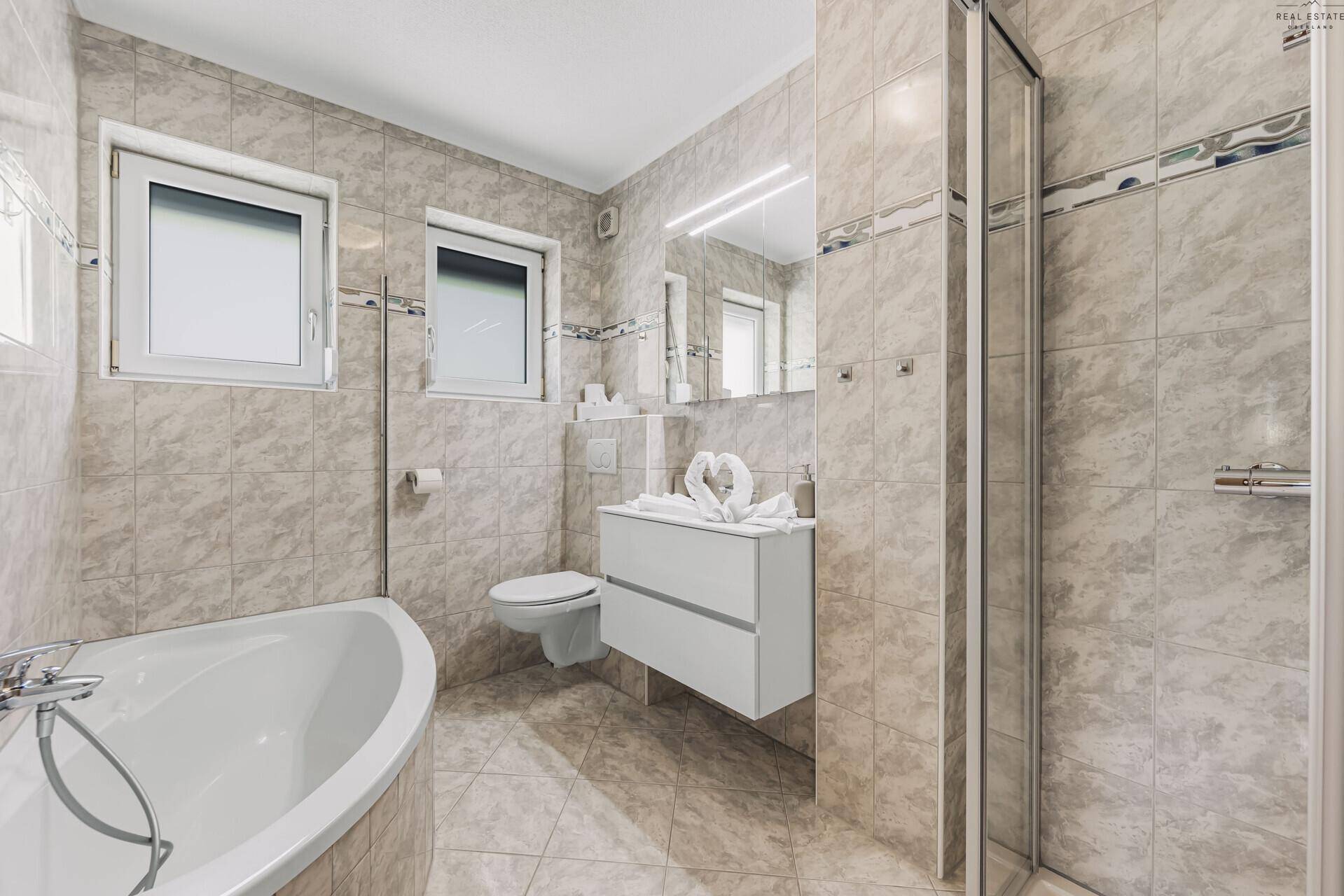 Modernes Badezimmer mit Eckbadewanne, Duschkabine und Doppelwaschbecken.