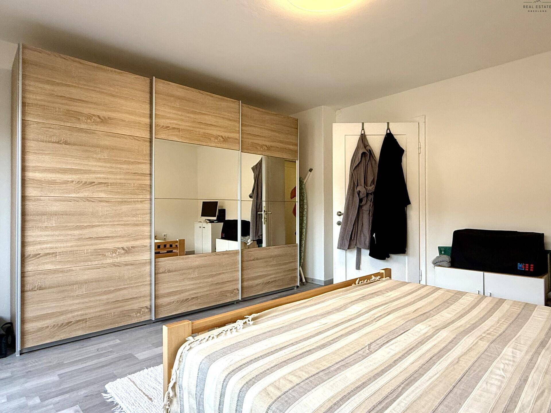 Schlafzimmer mit großem Kleiderschrank mit Spiegeltüren und Holzbett.