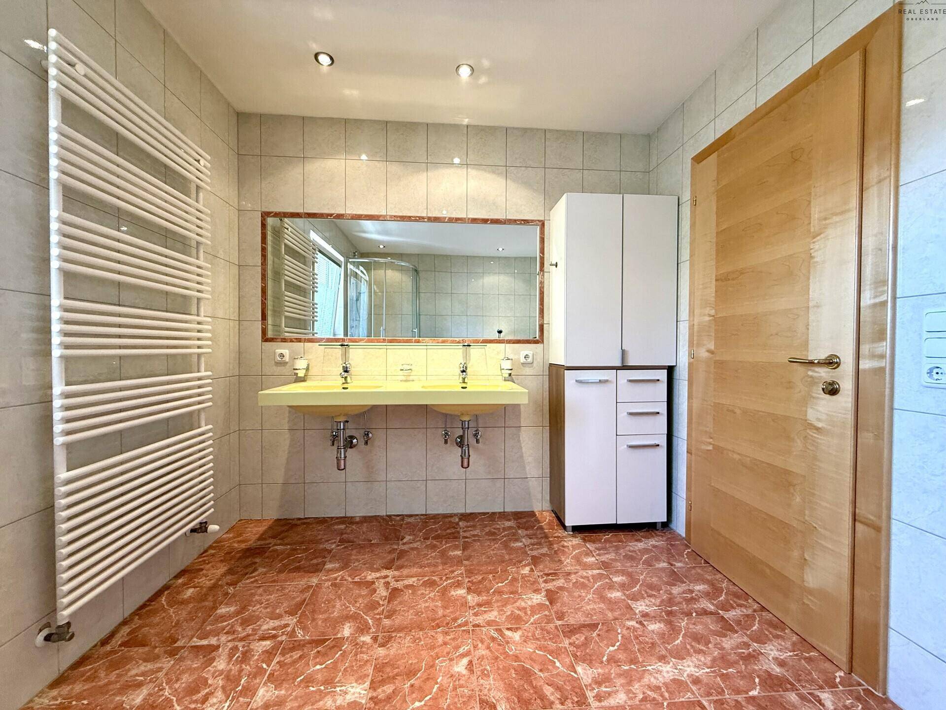Geräumiges Badezimmer mit Doppelwaschbecken, großem Spiegel und praktischem Handtuchheizkörper.