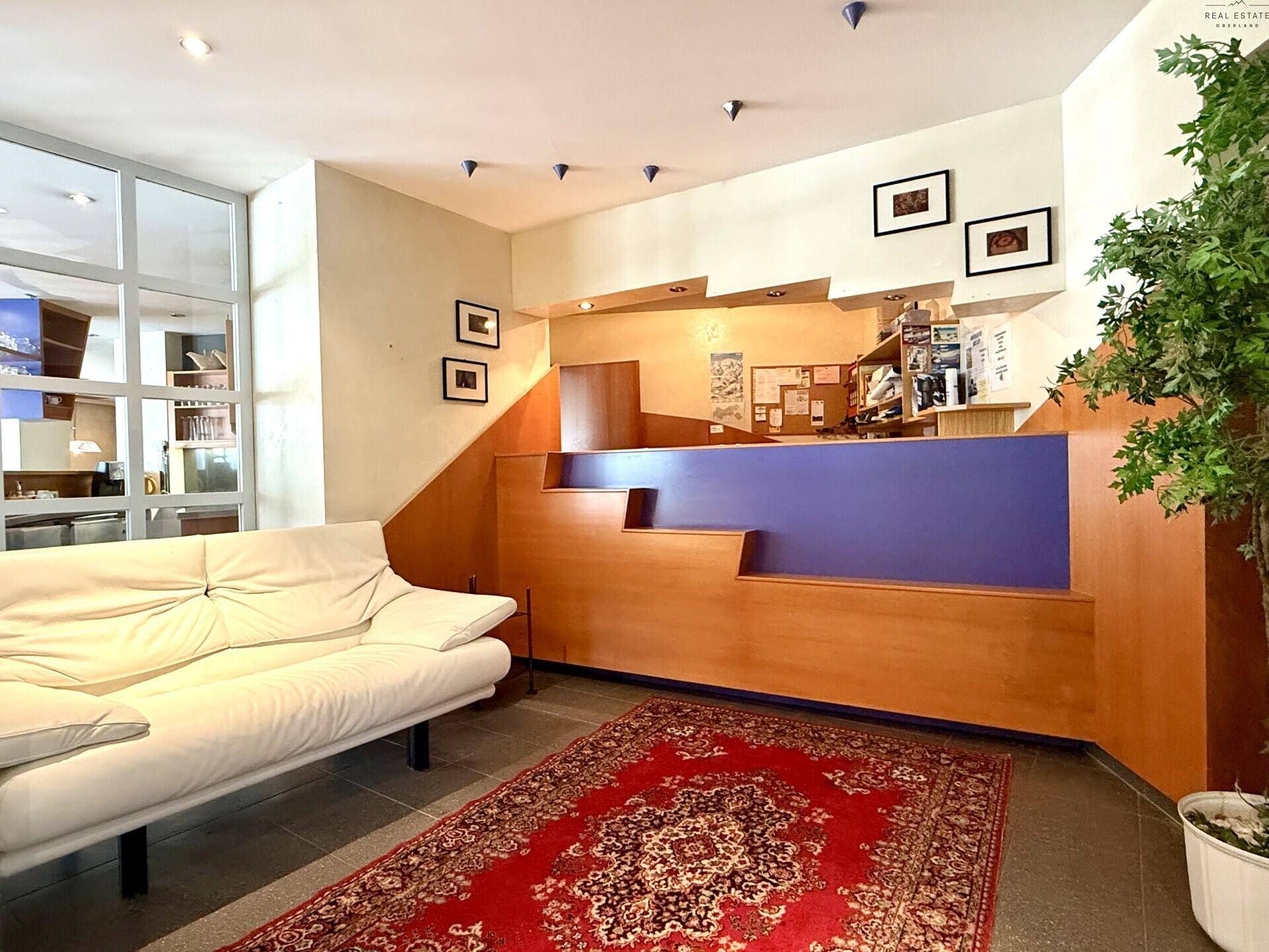 Detailansicht des Empfangsbereichs mit Rezeption, Sofa und dekorativem Teppich.