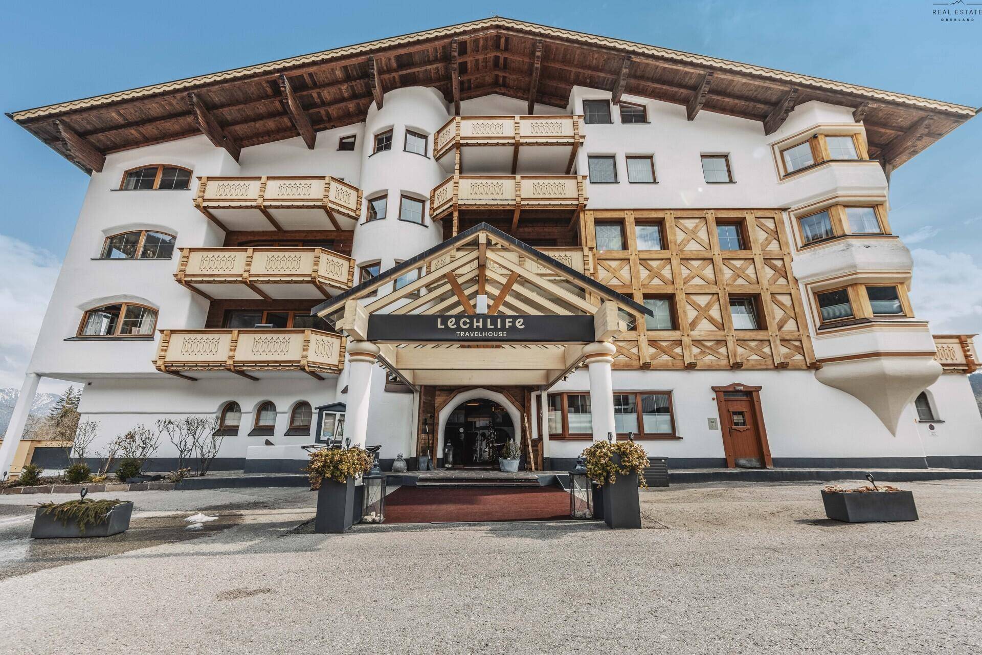 Elegante Hotelfassade im alpinen Stil mit Holzelementen und einem überdachten Eingangsbereich.