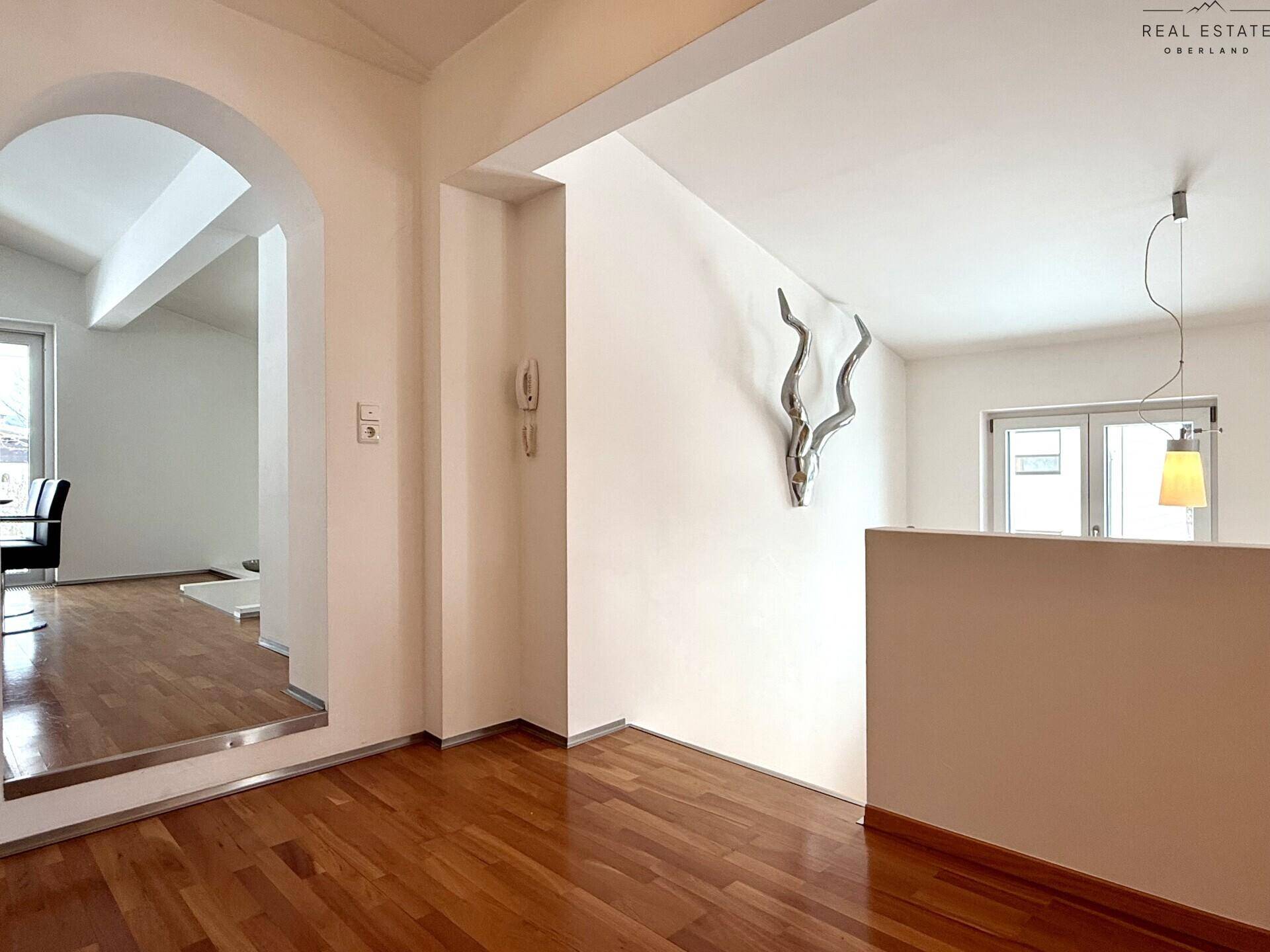 Heller Flurbereich mit Holzfußboden, einem eleganten Bogen und dekorativen Elementen an der Wand.