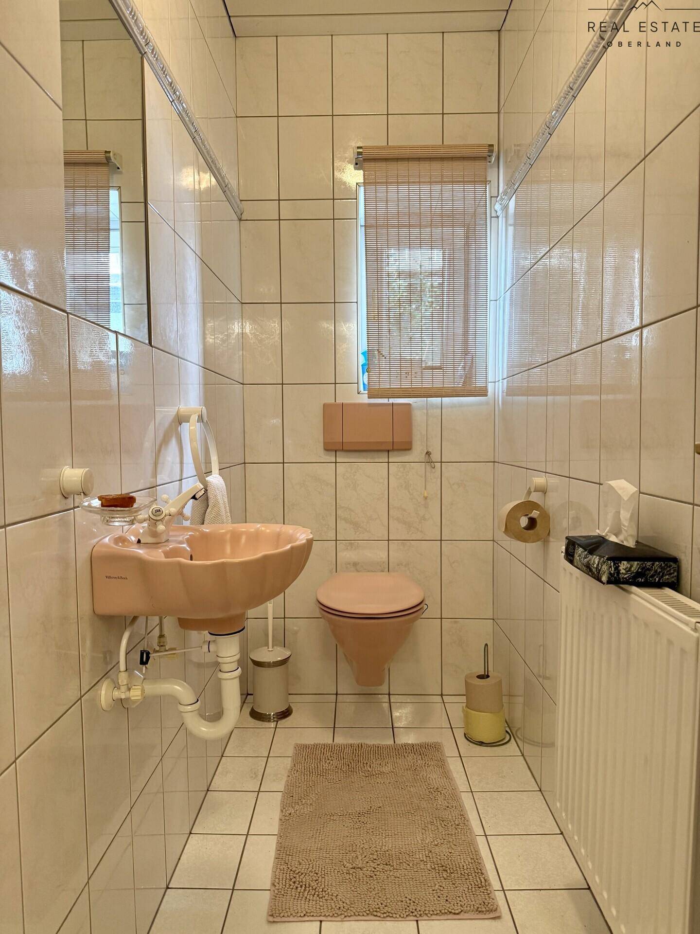 Kleines Gäste-WC mit rosa Sanitärobjekten und weißen Fliesen.