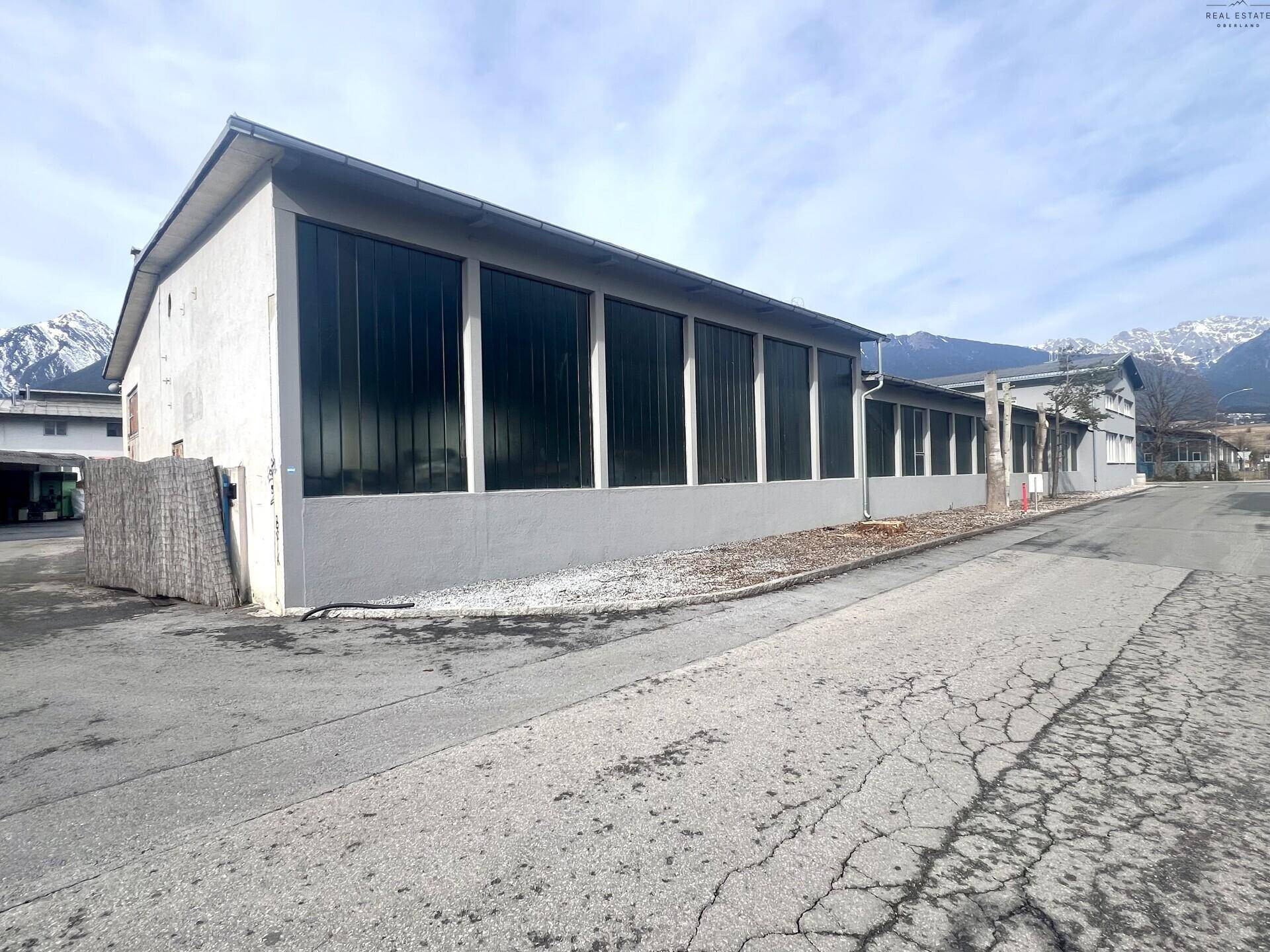 Rückansicht des Industriegebäudes mit hohen Fenstern und einem klaren Blick auf die umliegenden Berge.