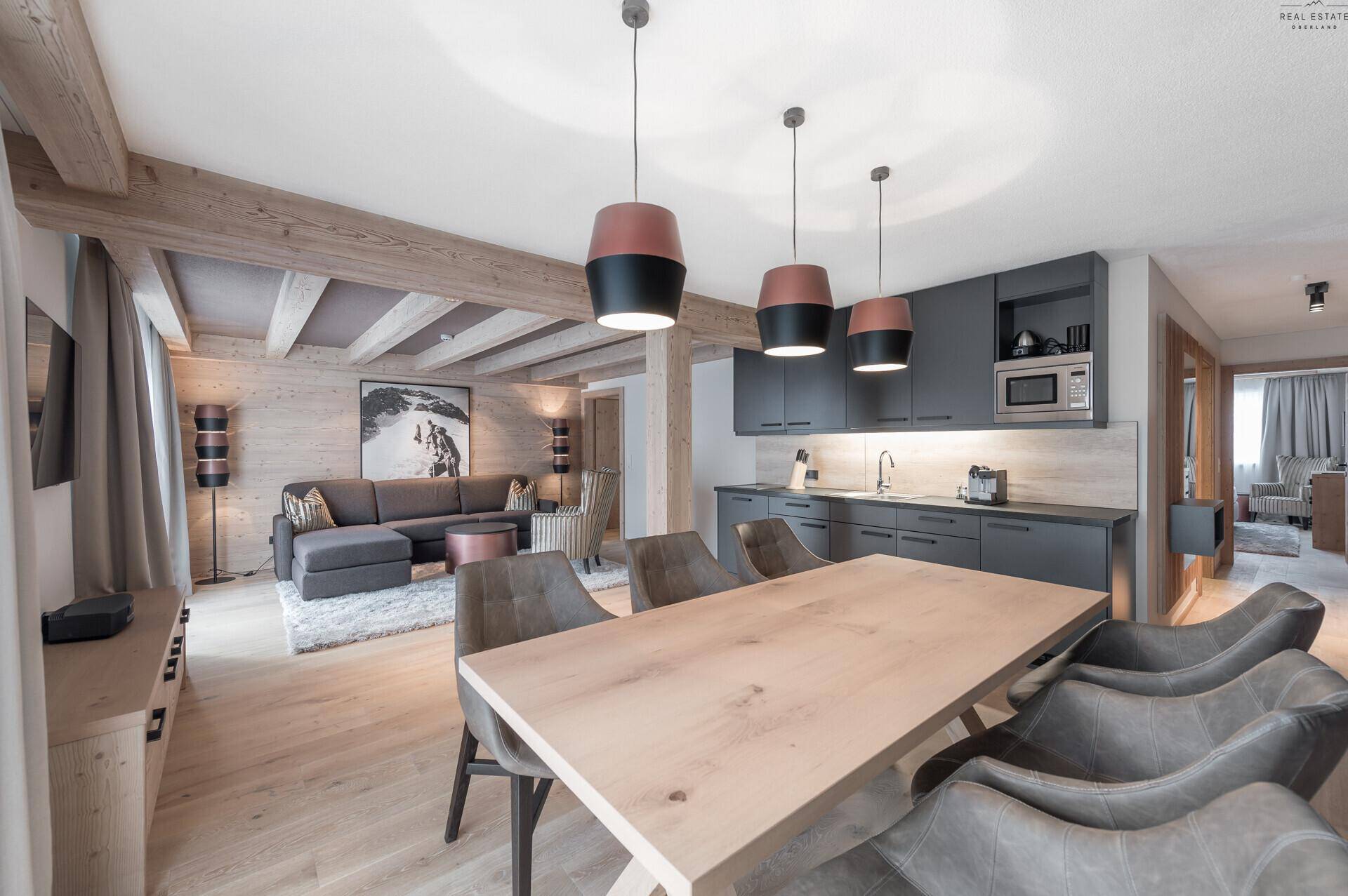 Gemütlicher Wohn-Essbereich mit offener Küche, Holzbalken und modernem Design in alpiner Atmosphäre.