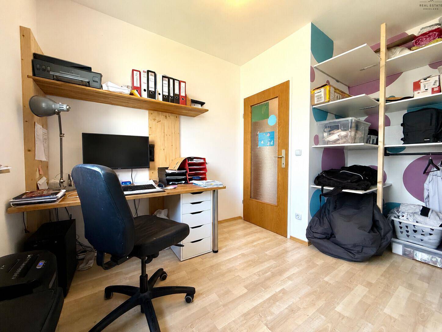 Praktisches Arbeitszimmer mit integriertem Schreibtisch, Wandregal und offenem Stauraum.