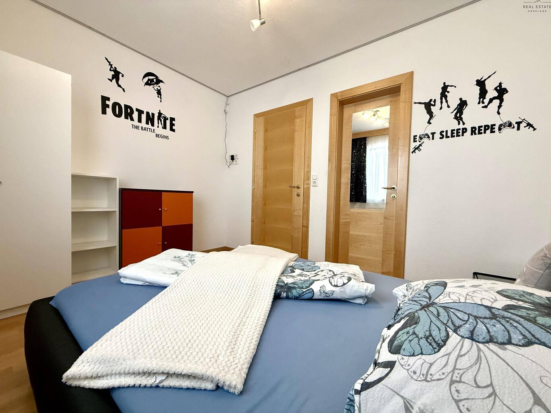 Kinderzimmer mit Bett, Holzüren und verspielter Wanddekoration.