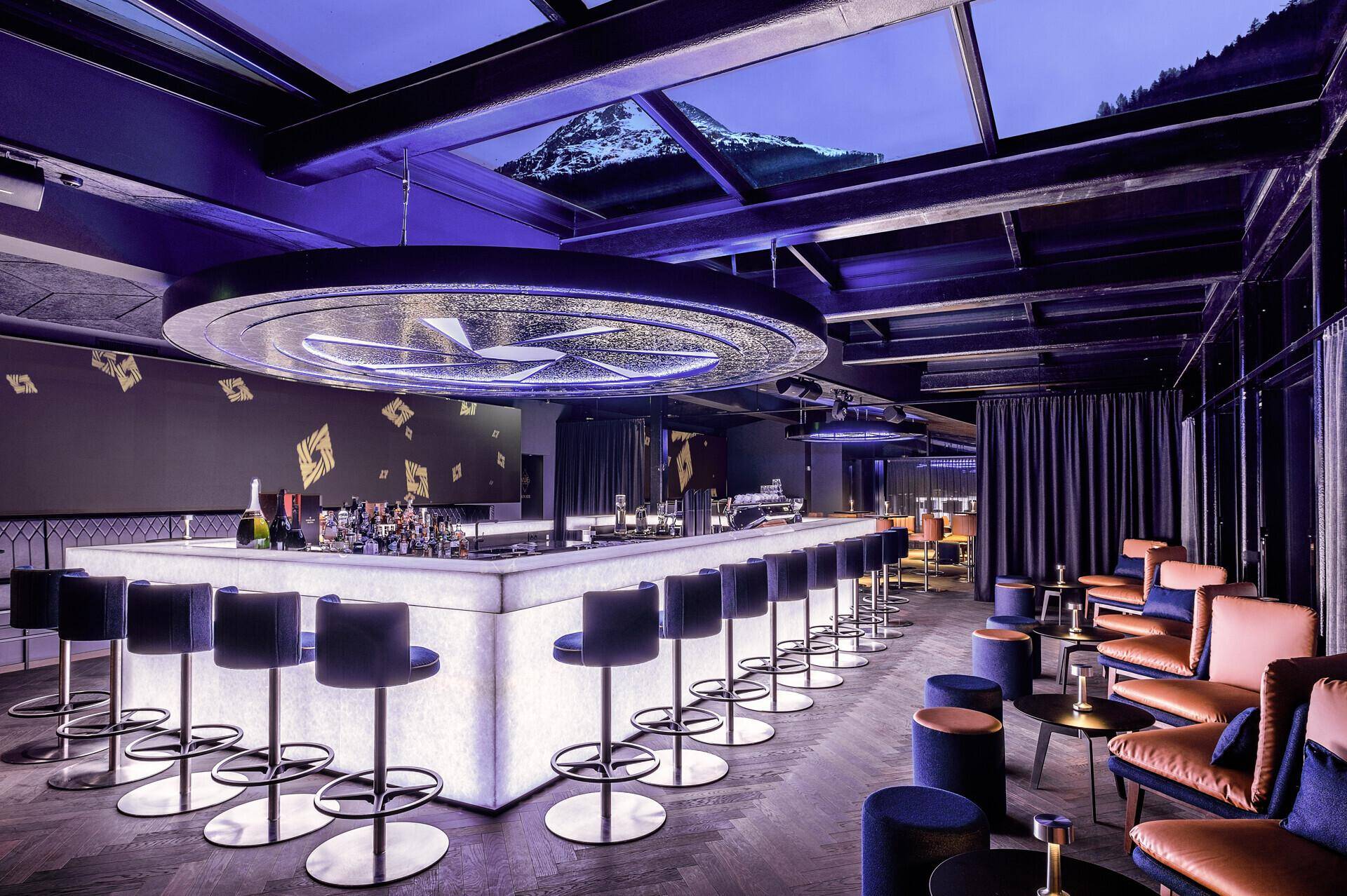 Elegante Bar mit stilvoller Beleuchtung, bequemen Barhockern und luxuriösem Ambiente.