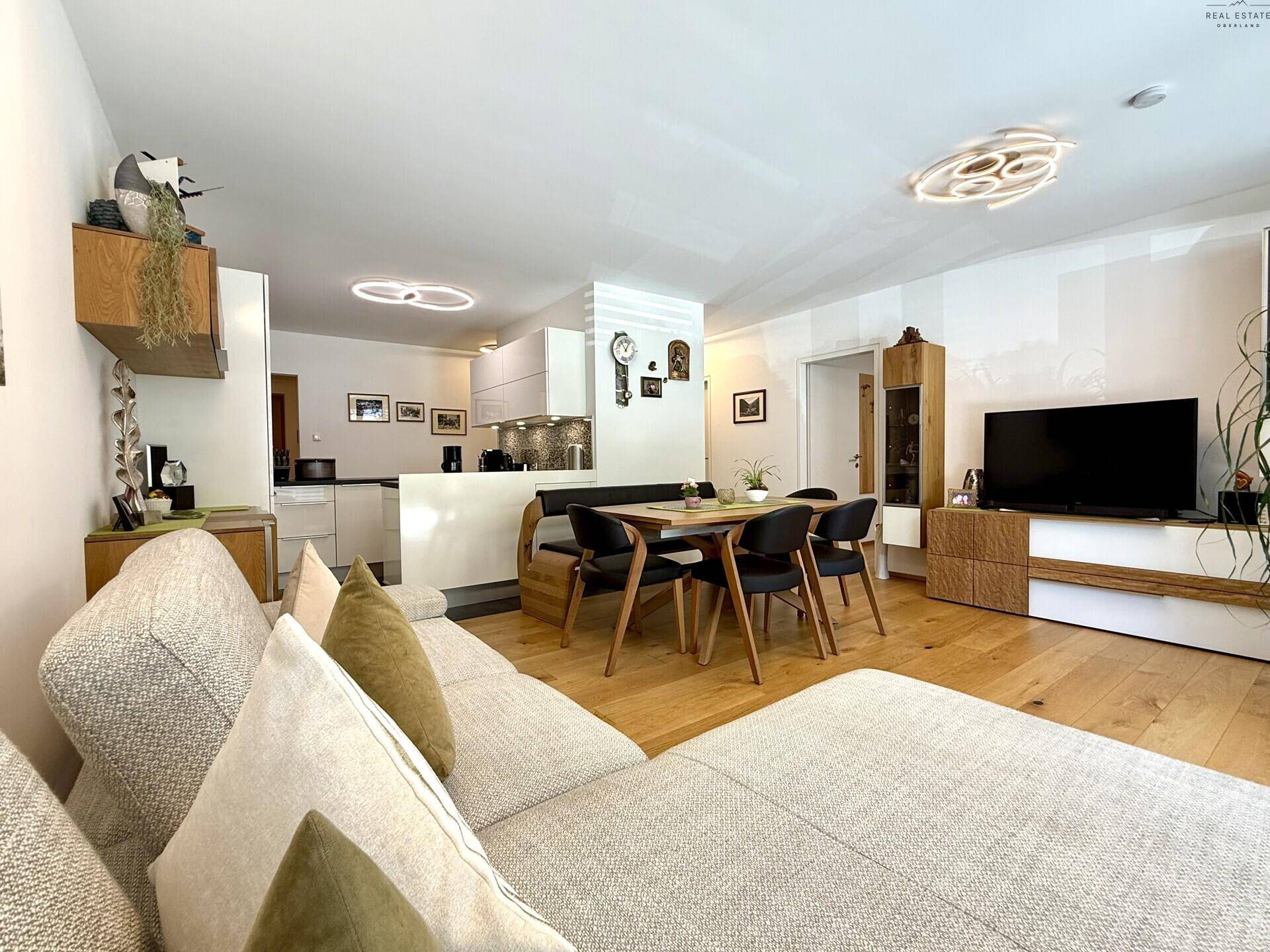 Offener Wohn-Essbereich mit Sofa, Esstisch und direktem Übergang zur modernen Küche.