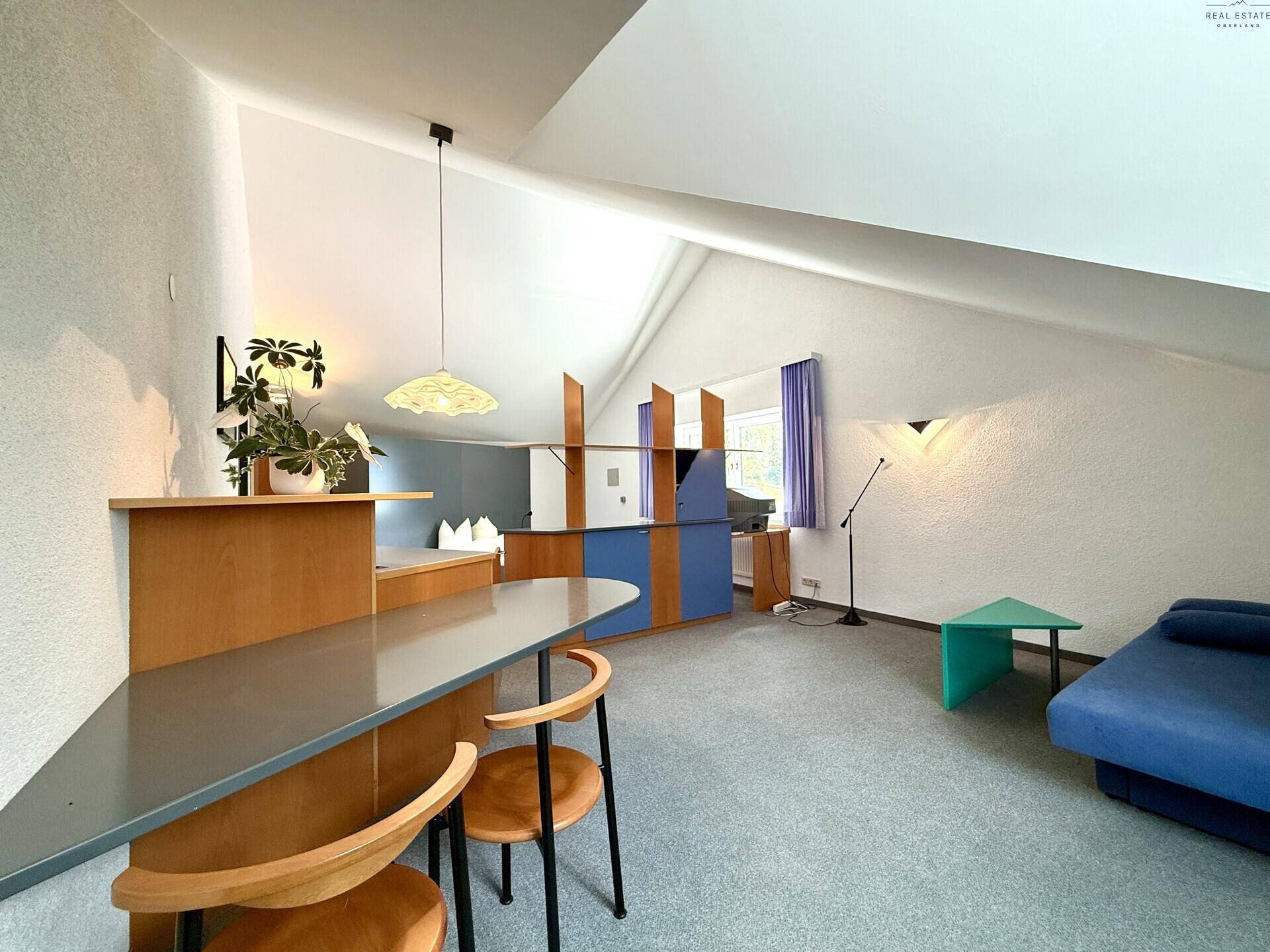 Helles Schlafzimmer im Dachgeschoss mit schrägen Wänden, Teppichboden und funktionalen Möbeln.