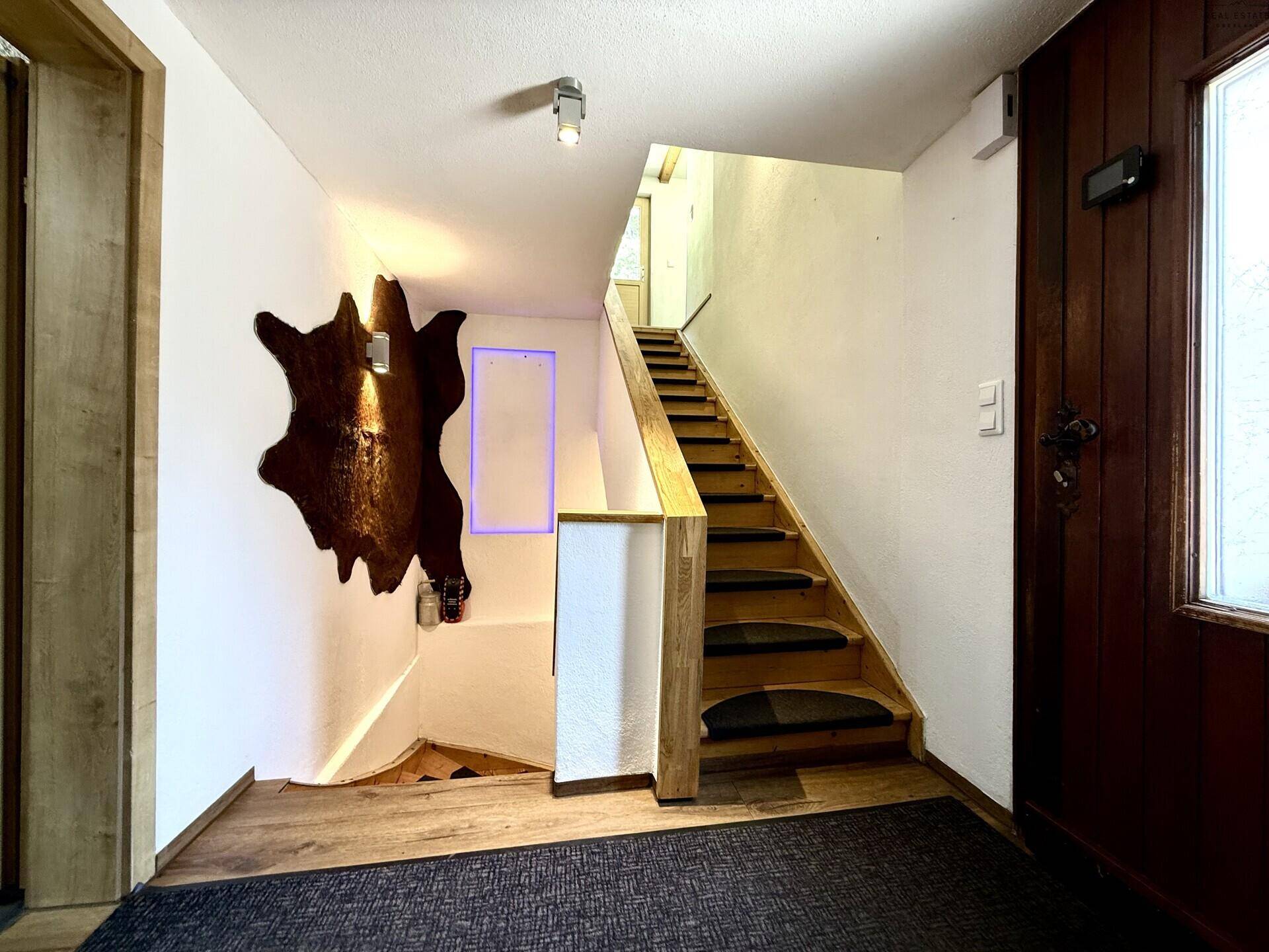 Treppenhaus mit Holzstufen und Geländer, führt in die oberen Etagen des Hauses.