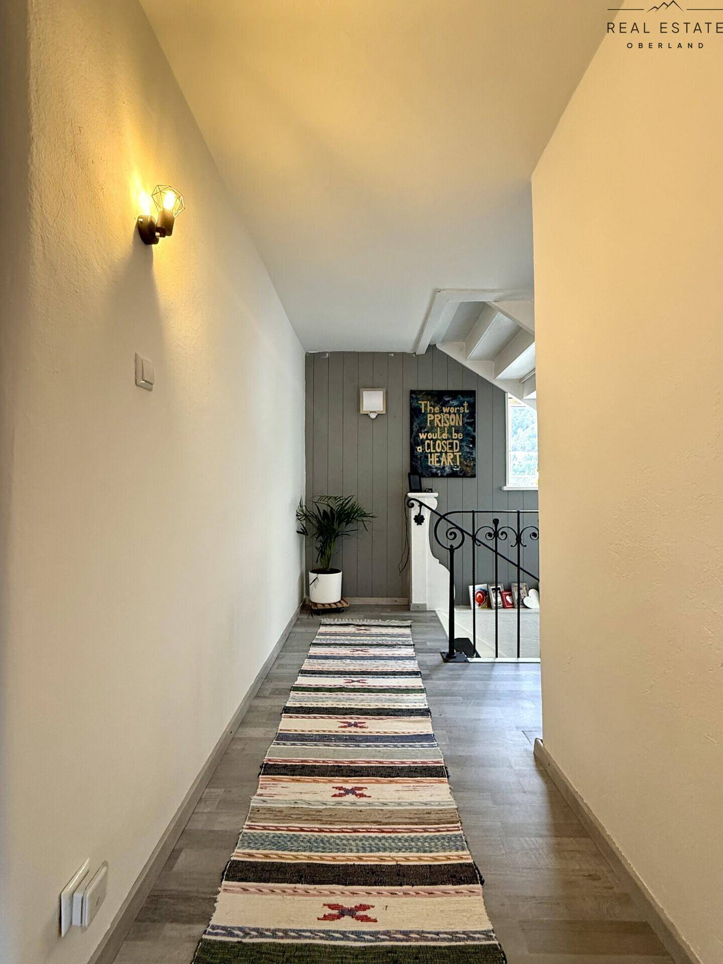 Oberer Flur mit Teppichläufer, weiß gestrichenen Wänden und Blick auf die Treppe.
