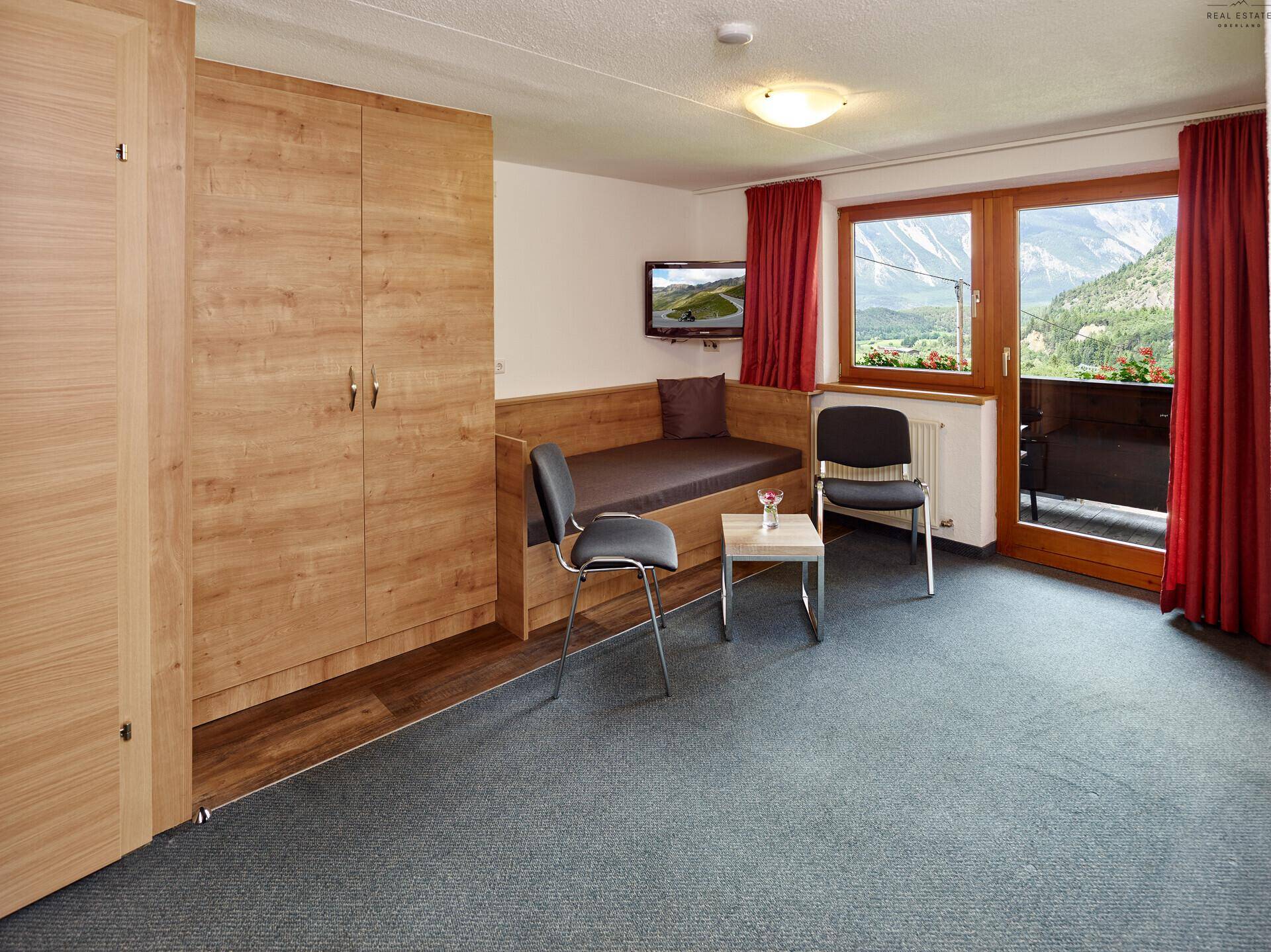Geräumiges Schlafzimmer mit Holzeinbauschränken, Tagesbett und Zugang zu einem Balkon.