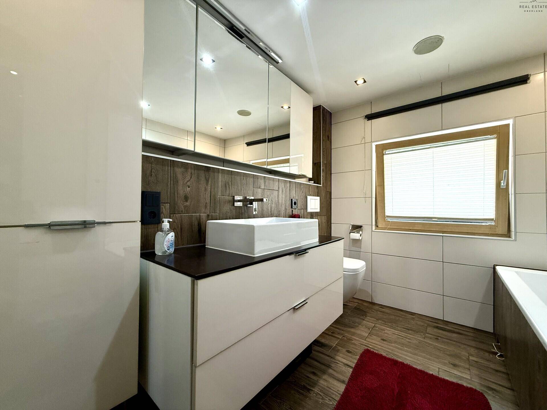 Elegantes Badezimmer mit modernem Waschbecken, Spiegelschrank und Fenster, hell und geräumig.