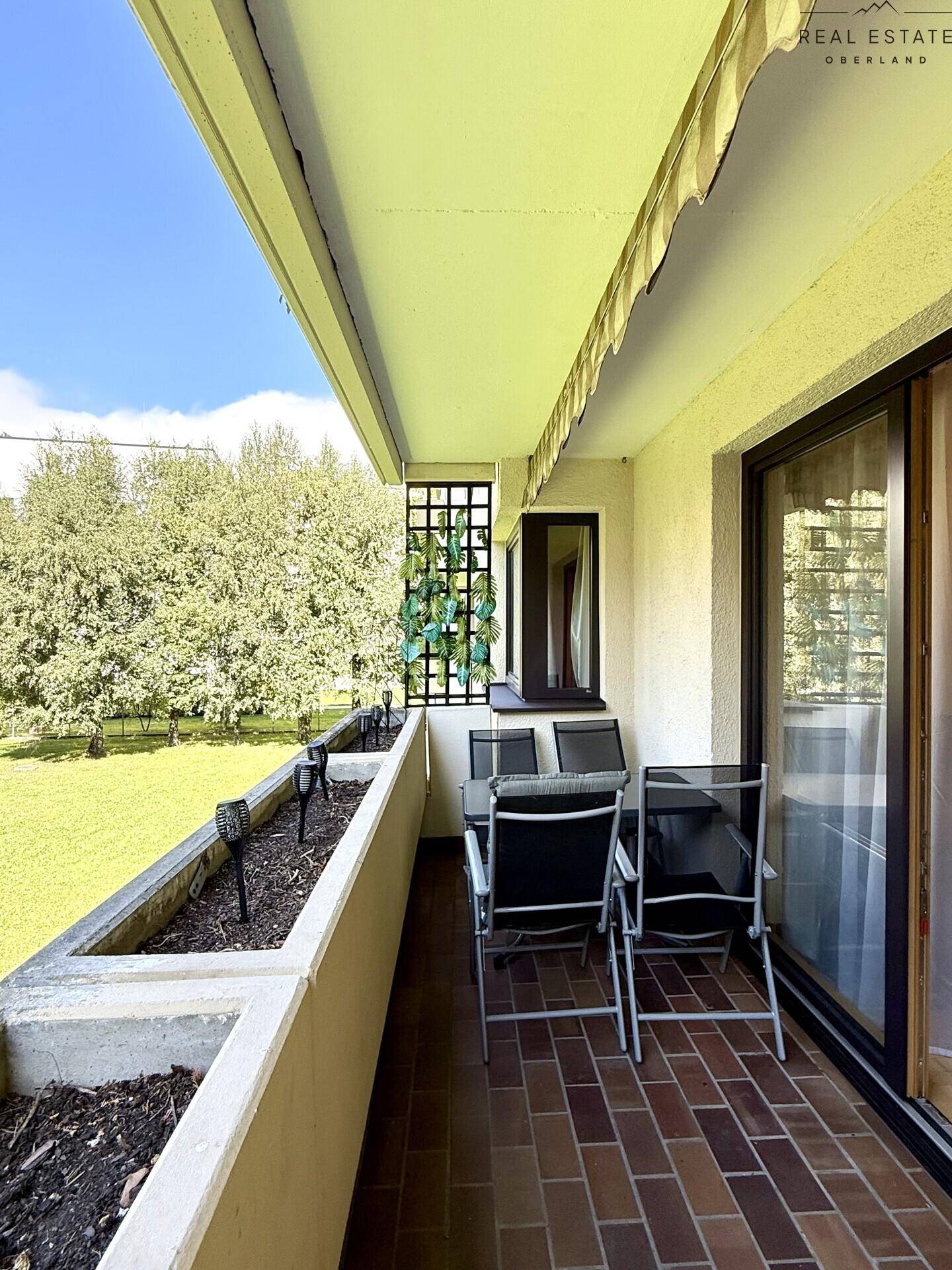 Balkon mit Sitzgelegenheiten und Blick auf eine weitläufige Rasenfläche.