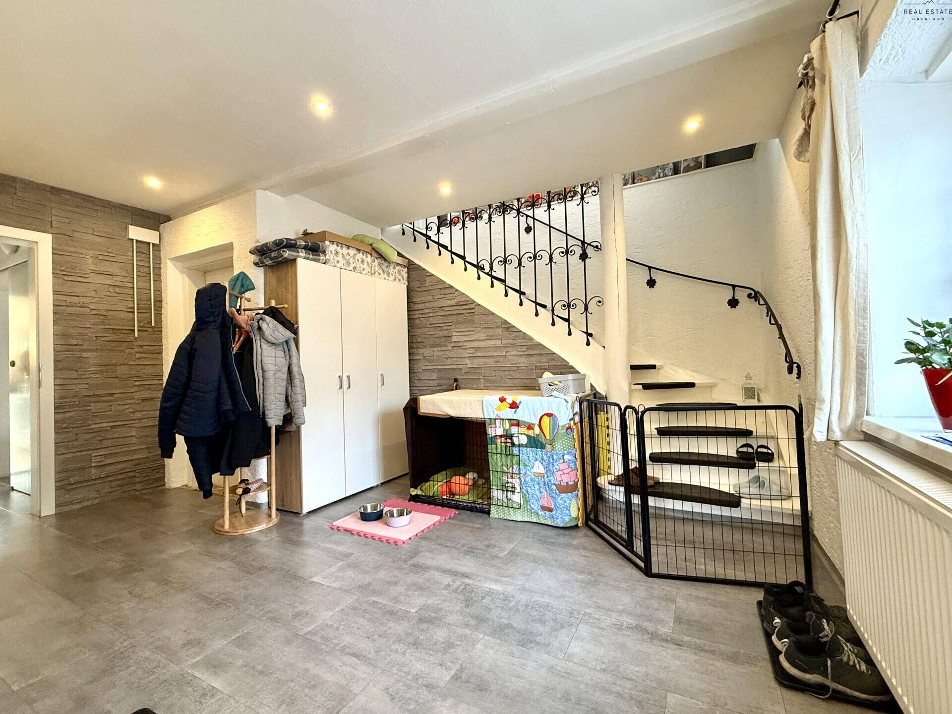 Eingangsbereich mit Garderobe, Treppe und modernem Fliesenboden.