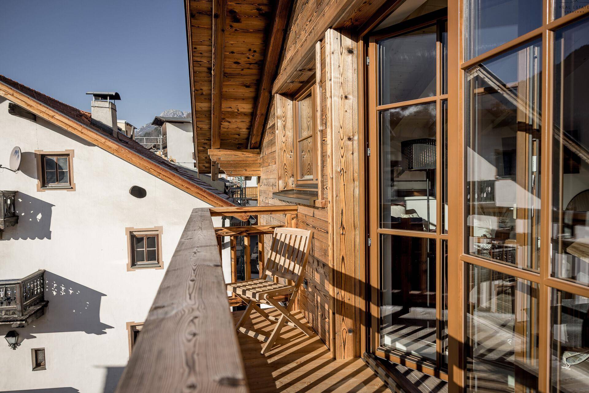 Geräumiger Holzbalkon mit Sitzgelegenheit und Zugang zu den Innenräumen.