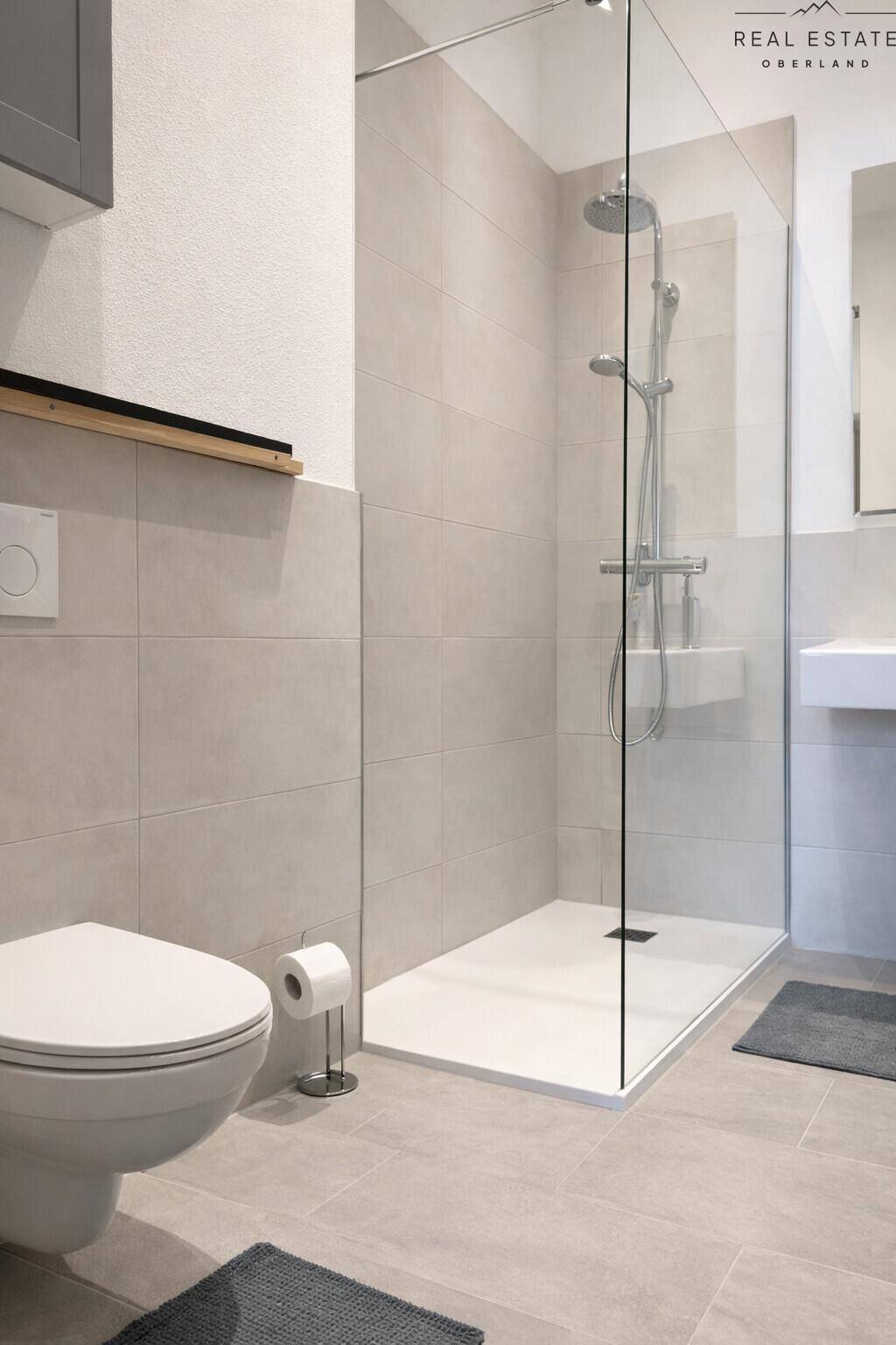 Modernes Badezimmer mit ebenerdiger Dusche und wandhängendem WC, in hellen Fliesen gehalten.