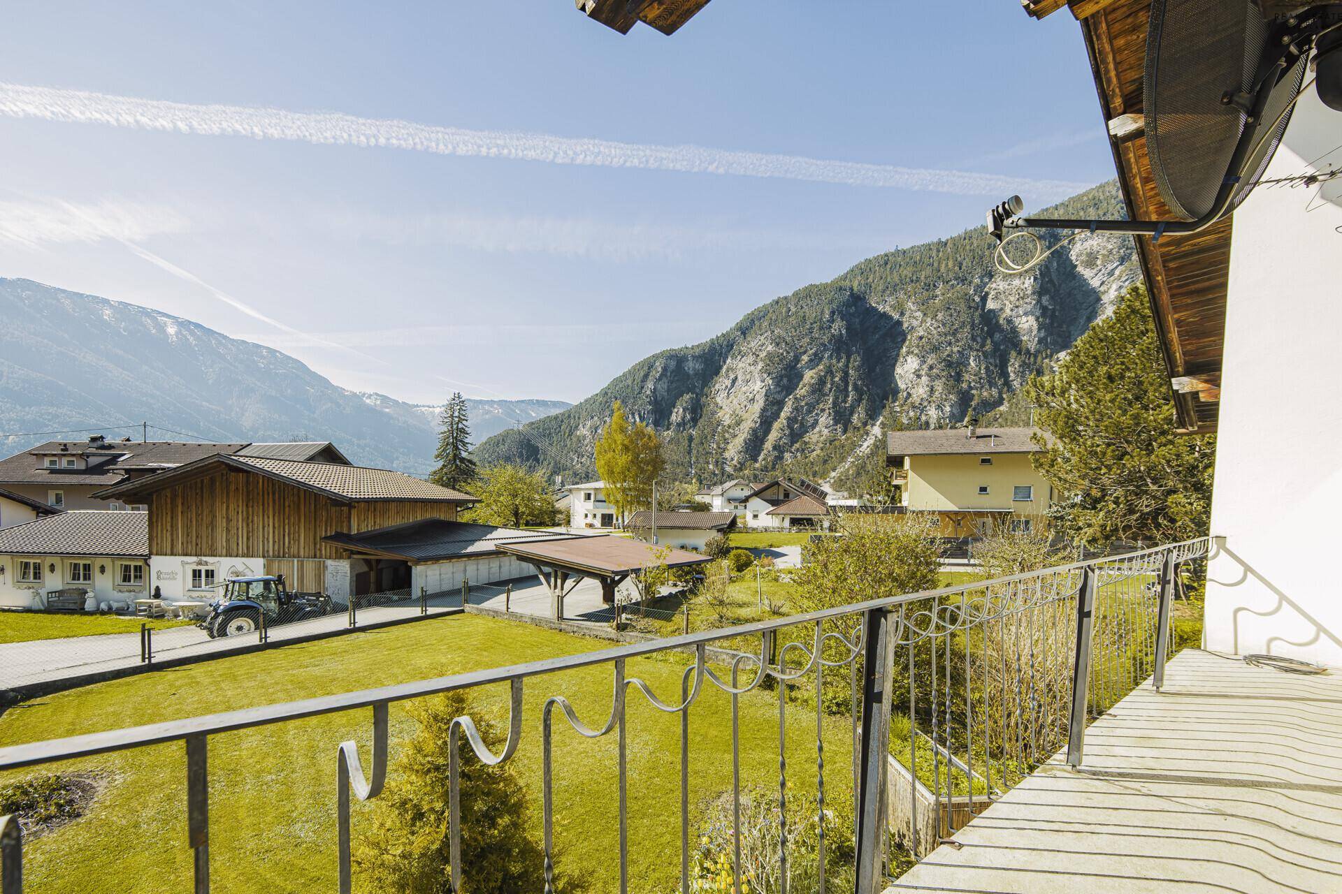 Balkon mit weitem Blick über die grüne Landschaft und die umliegenden Berge.