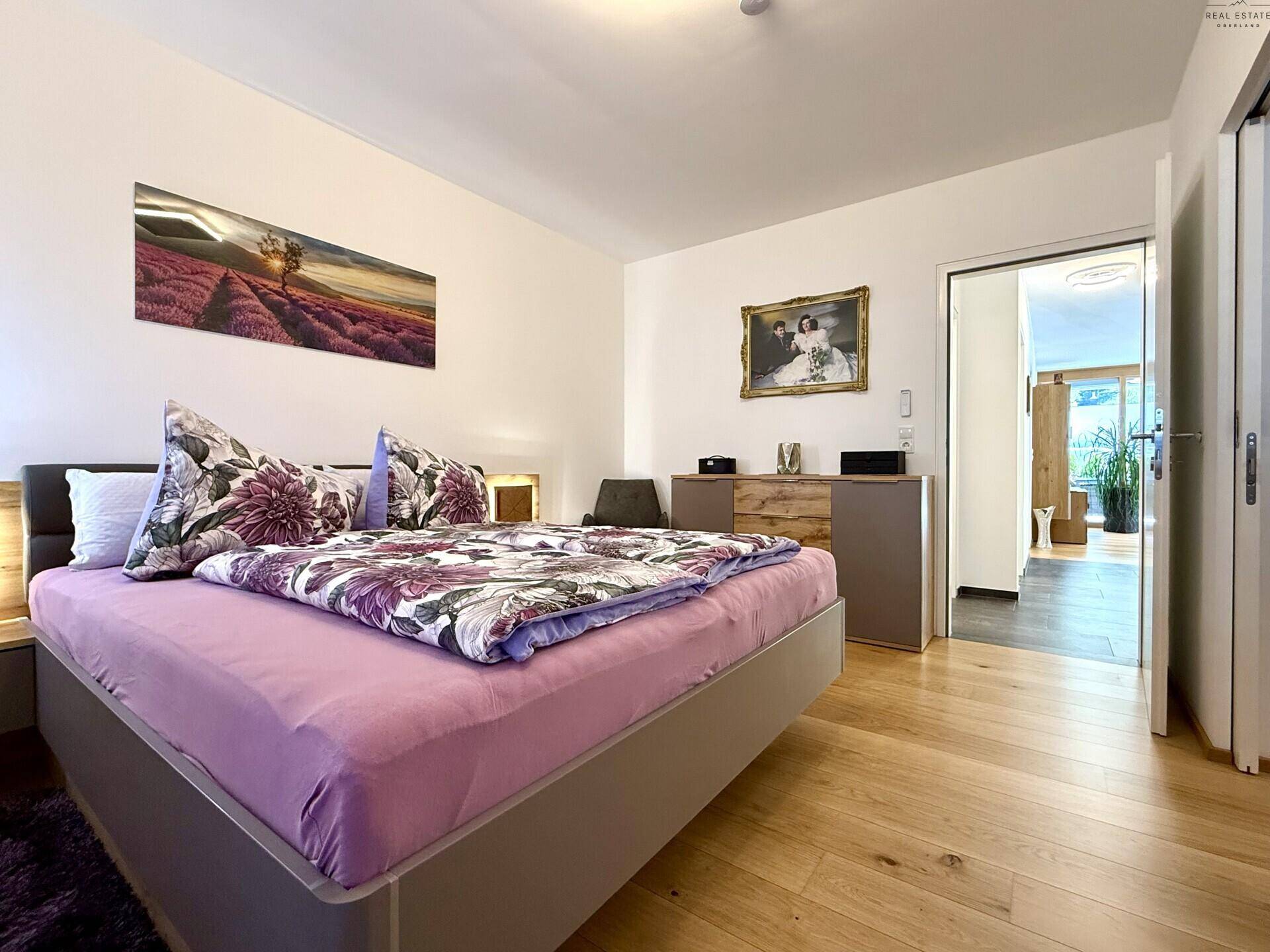 Gemütliches Schlafzimmer mit Holzboden und Zugang zu weiteren Räumen.
