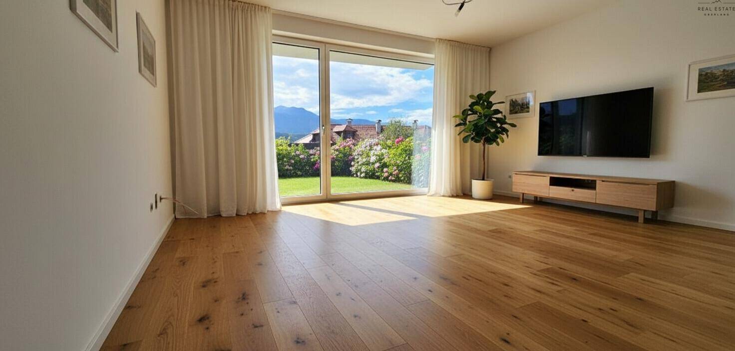 Helles Wohnzimmer mit Holzboden, großen Fenstern und Zugang zum Garten.